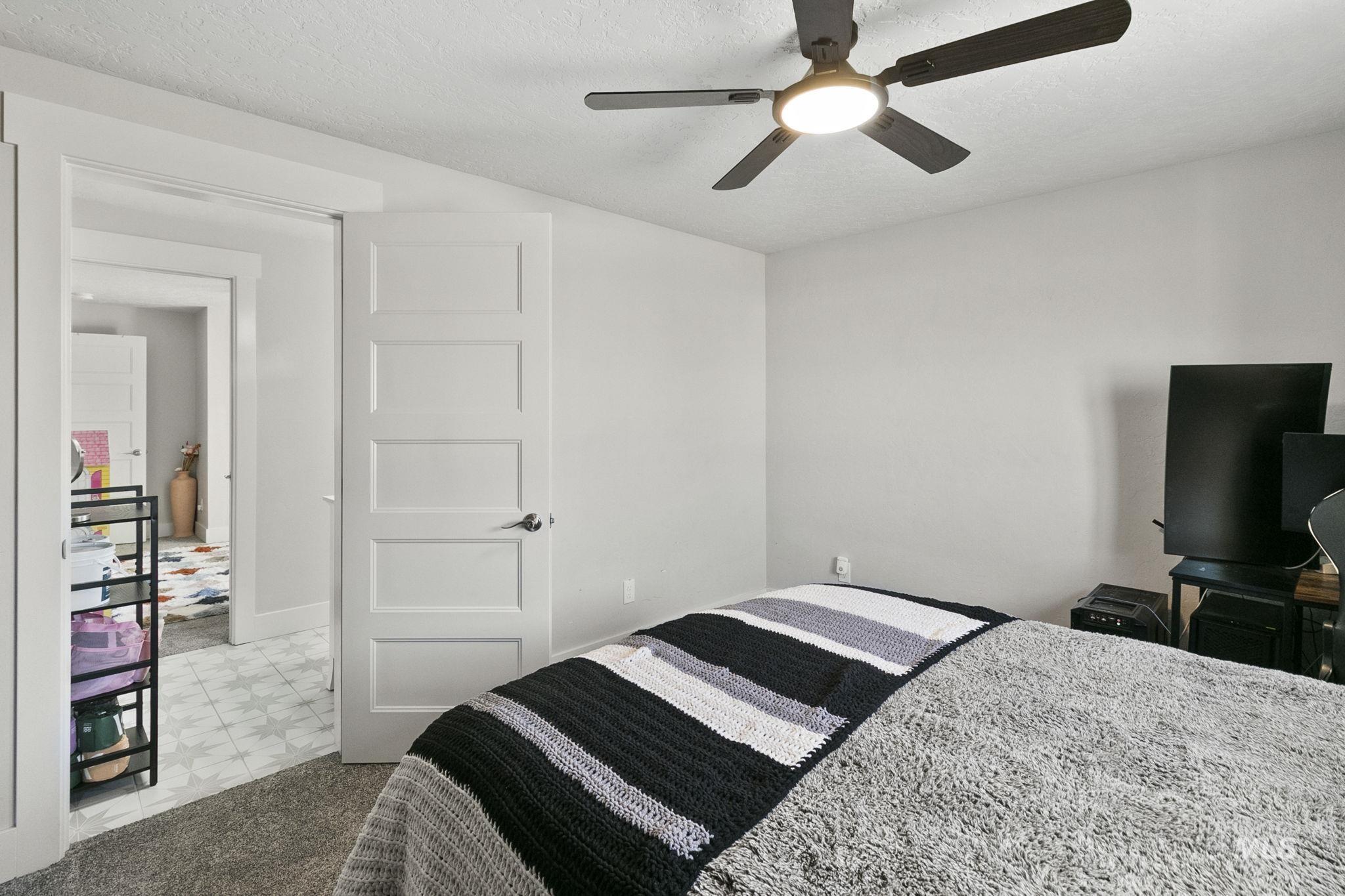 Bedroom with ceiling fan, a textured ceiling, and light carpet