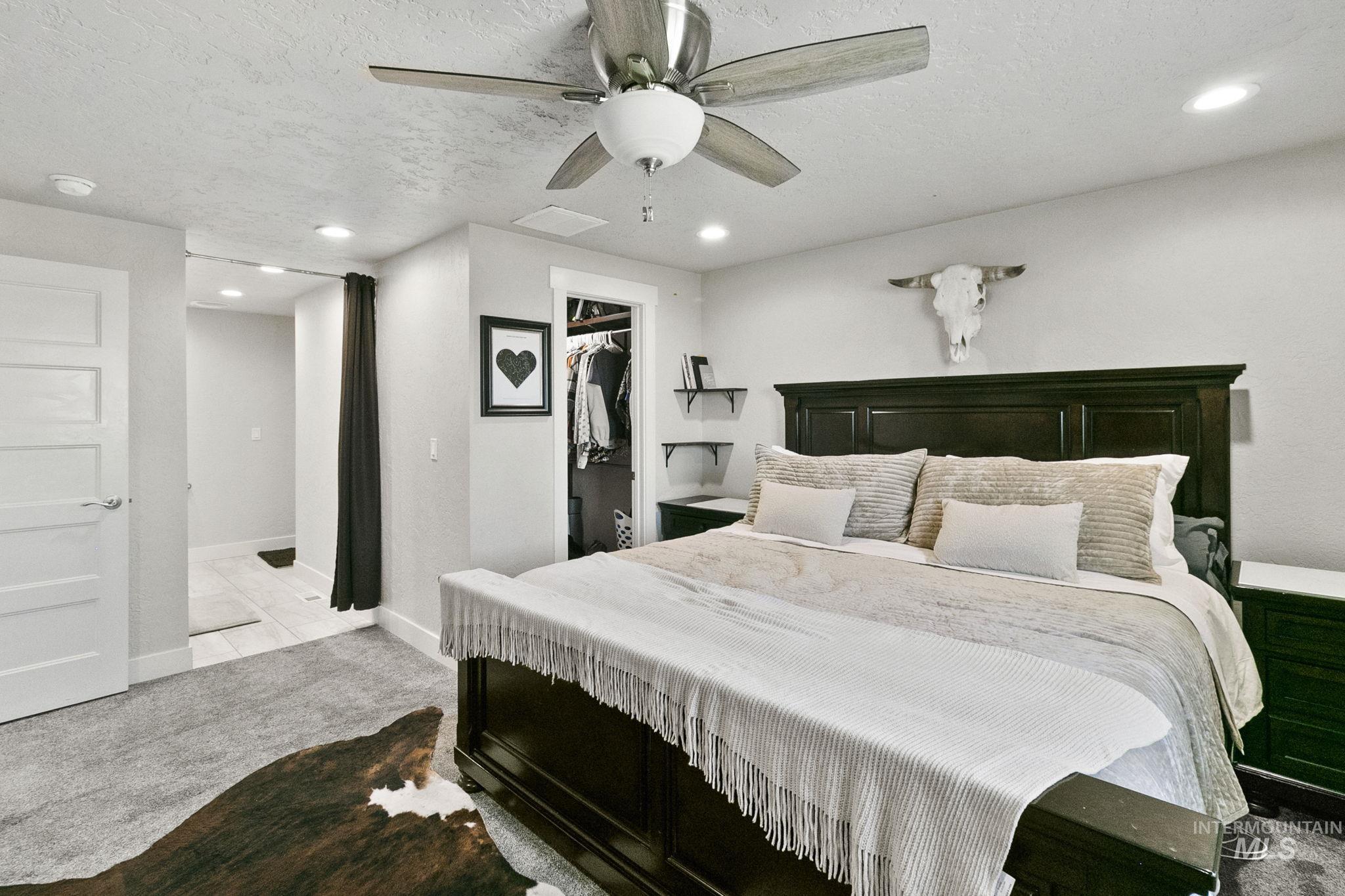 Carpeted bedroom featuring a walk in closet, recessed lighting, a ceiling fan, and a textured ceiling