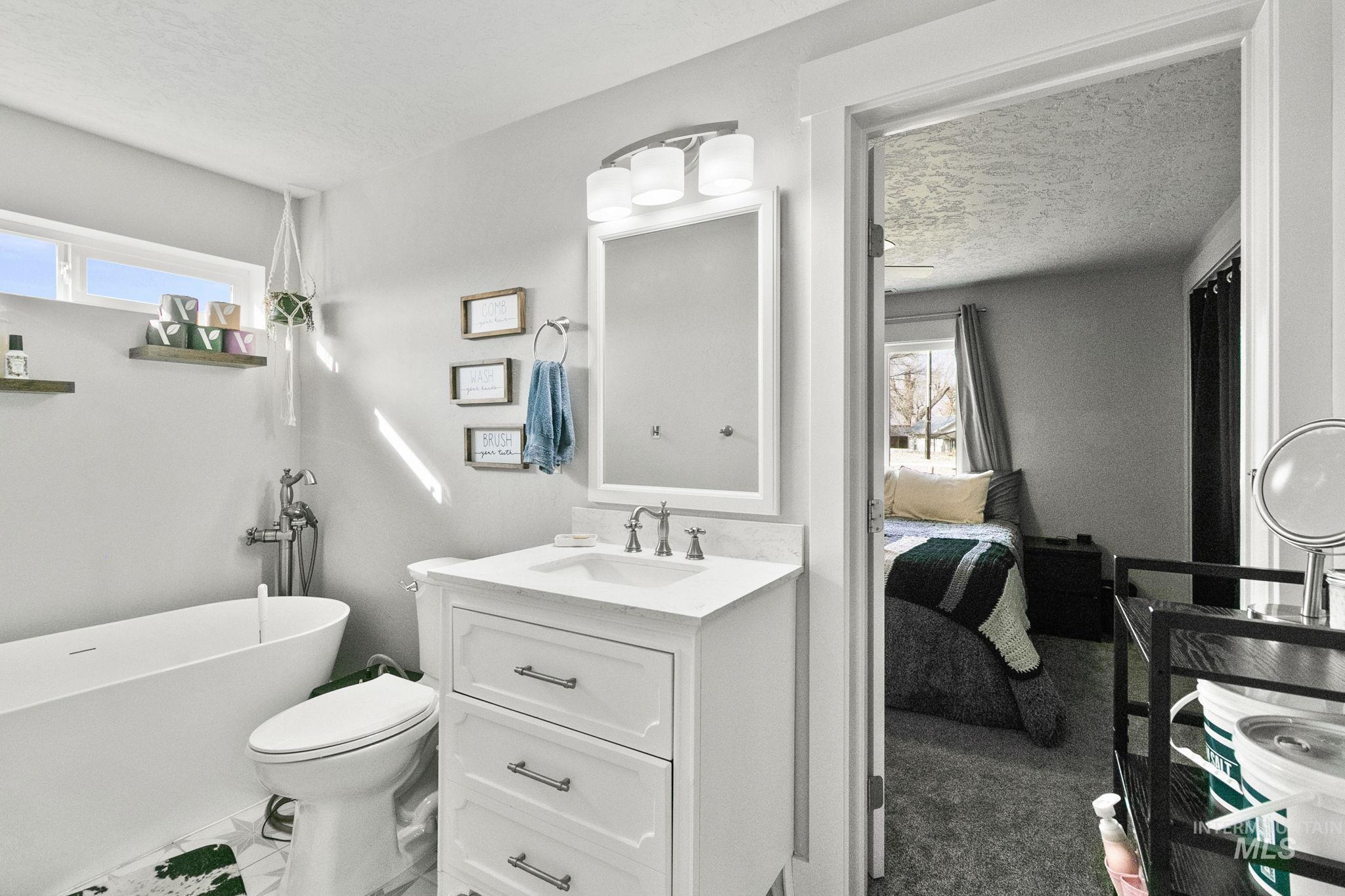 Bathroom featuring a textured ceiling, a soaking tub, healthy amount of natural light, and vanity