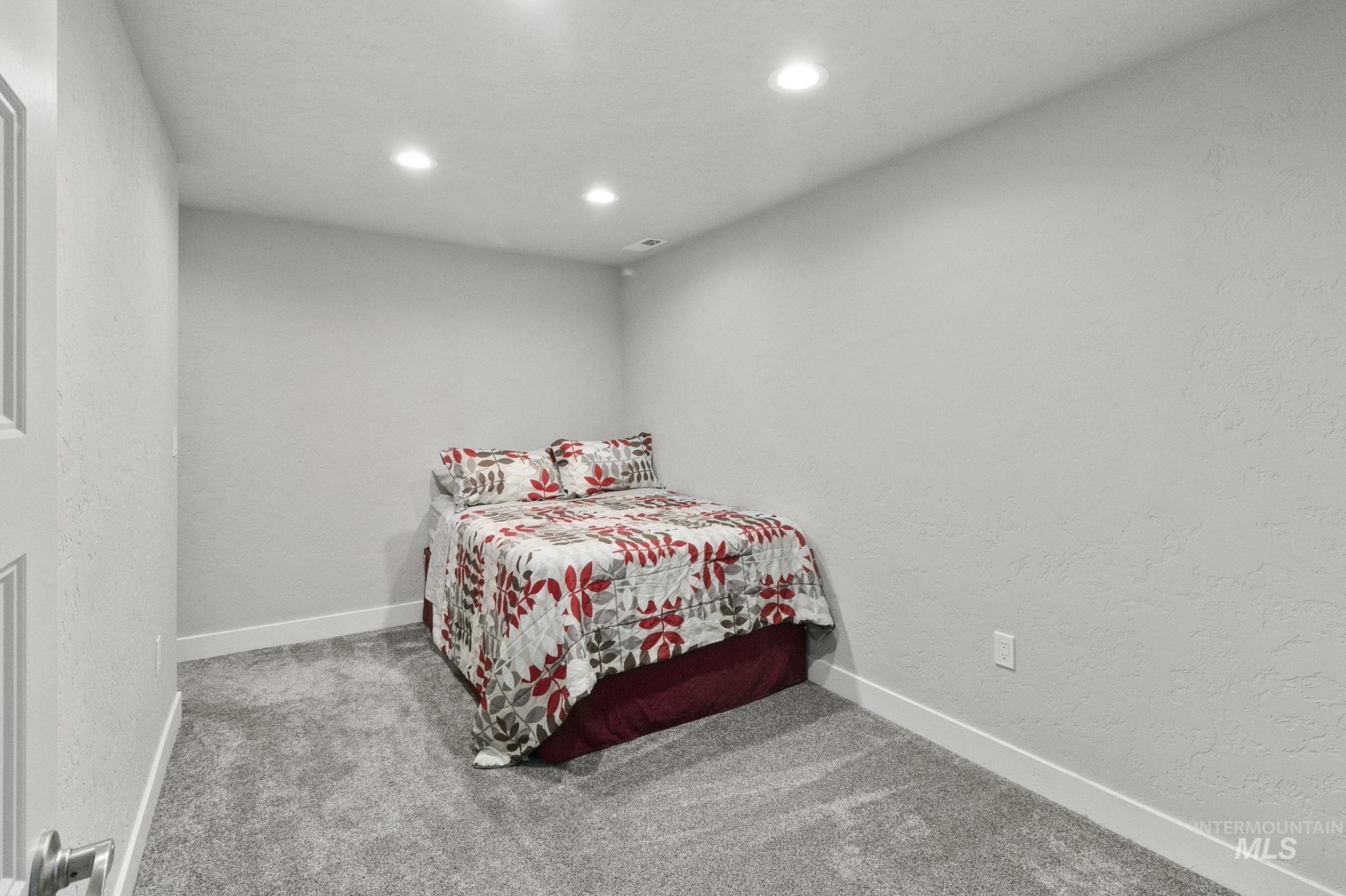 Carpeted bedroom featuring a textured wall and recessed lighting