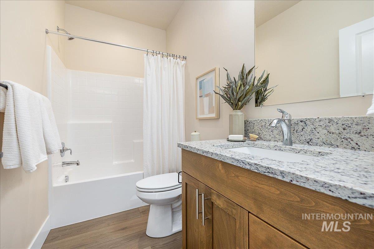 Full bathroom with dark wood-style floors, shower / bath combo, and vanity