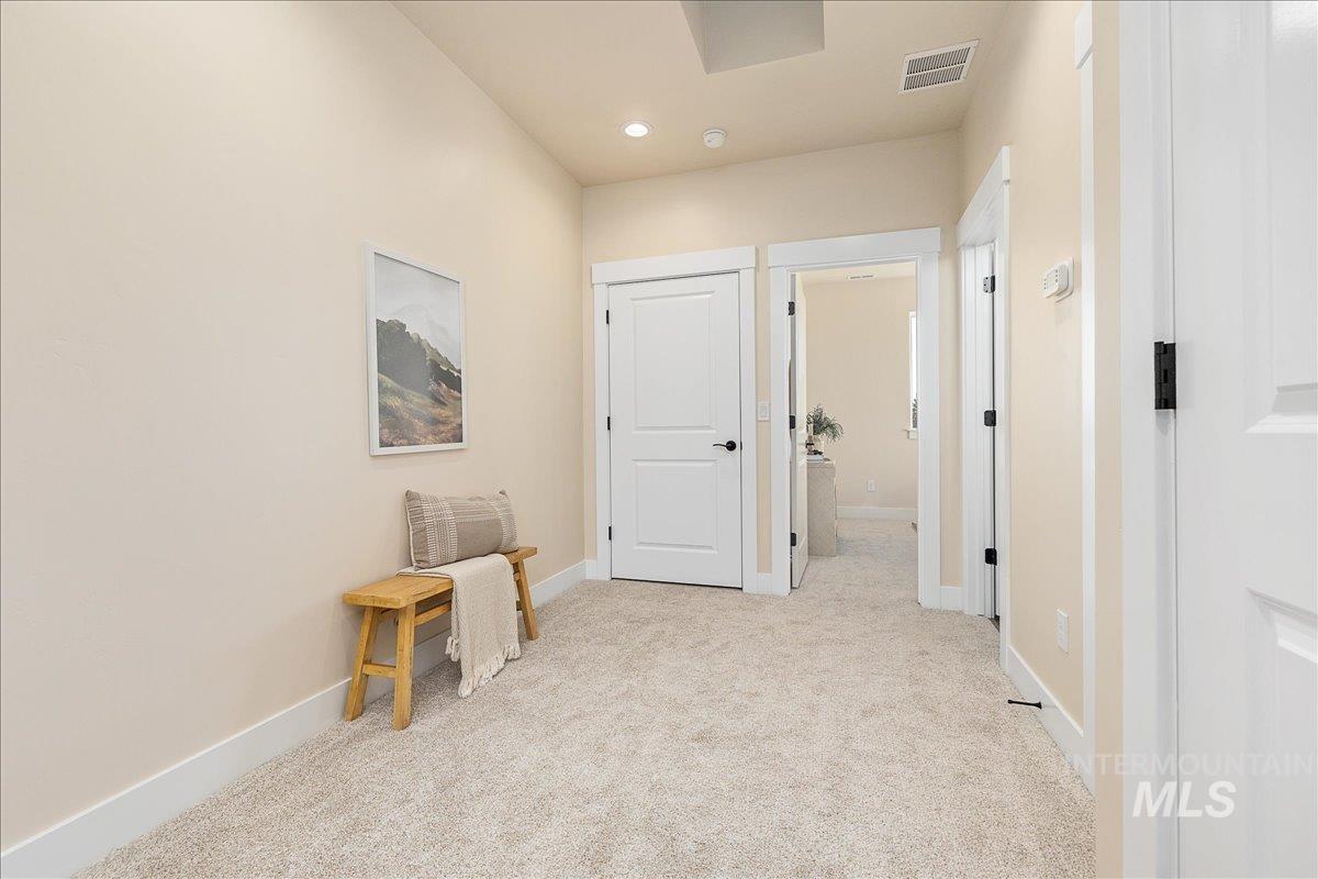 Corridor featuring light colored carpet and baseboards