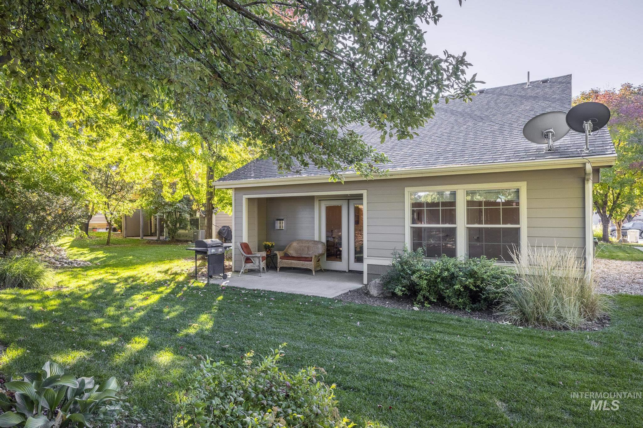 Back of property featuring a patio, a shingled roof, and a lawn