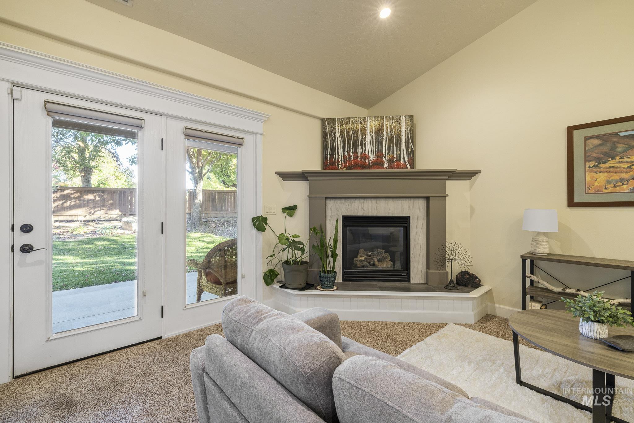 Carpeted living room featuring lofted ceiling and a tile fireplace