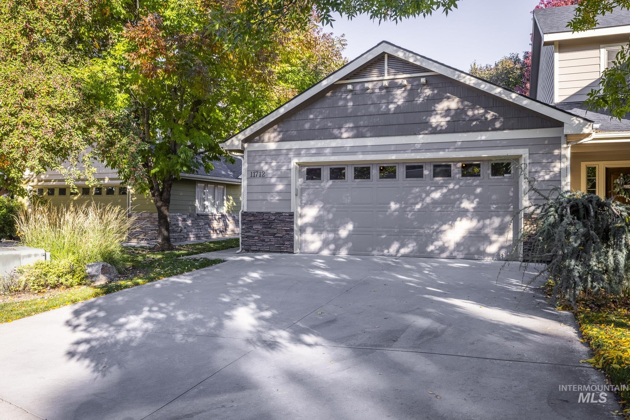 View of front of home featuring stone siding, concrete driveway, and a garage