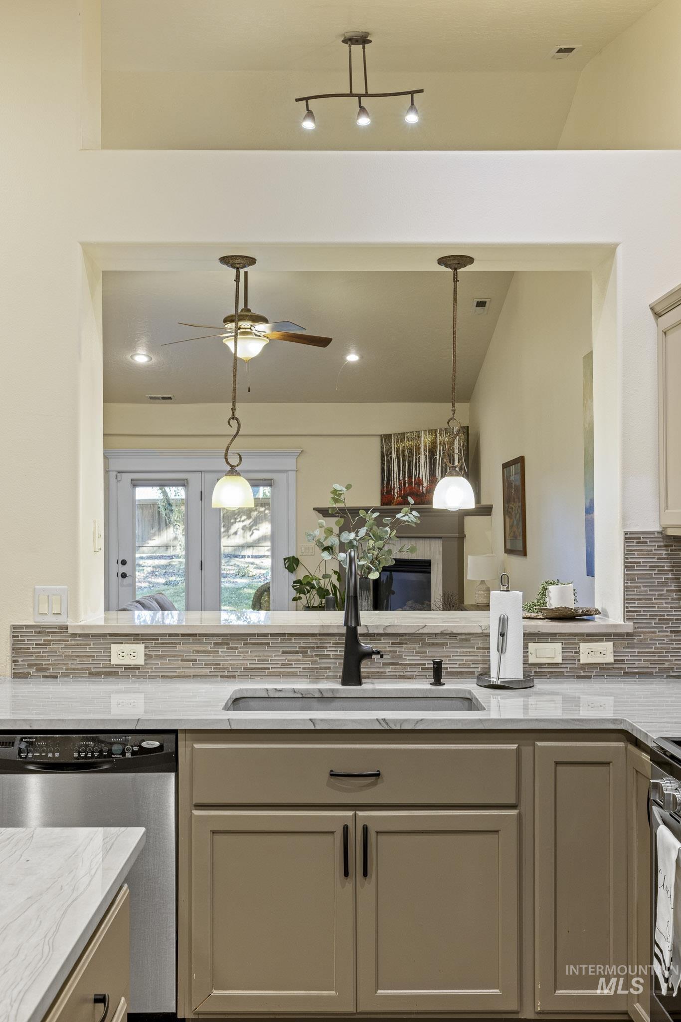 Kitchen with tasteful backsplash, a peninsula, appliances with stainless steel finishes, light stone counters, and lofted ceiling