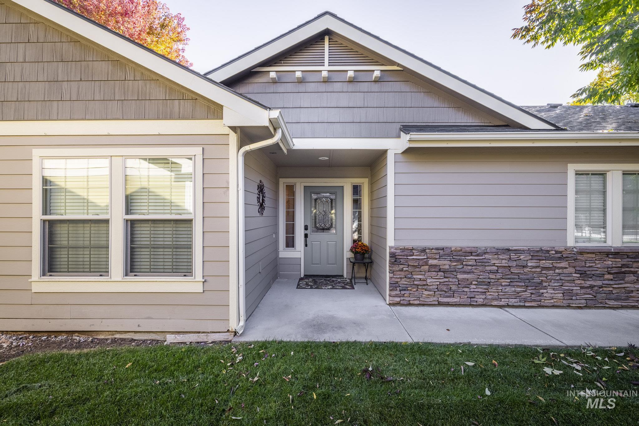 Property entrance featuring stone siding, a lawn, and roof with shingles