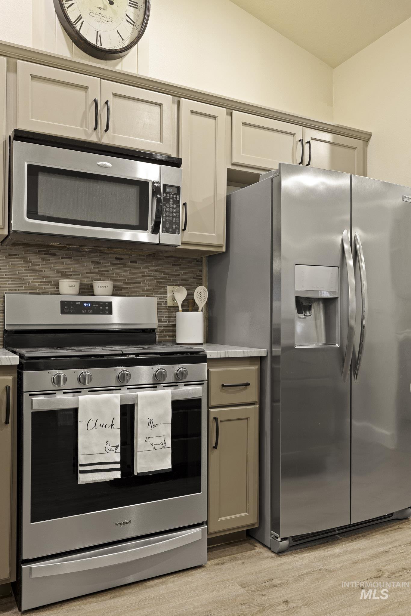 Kitchen featuring stainless steel appliances, decorative backsplash, light wood-type flooring, and gray cabinetry