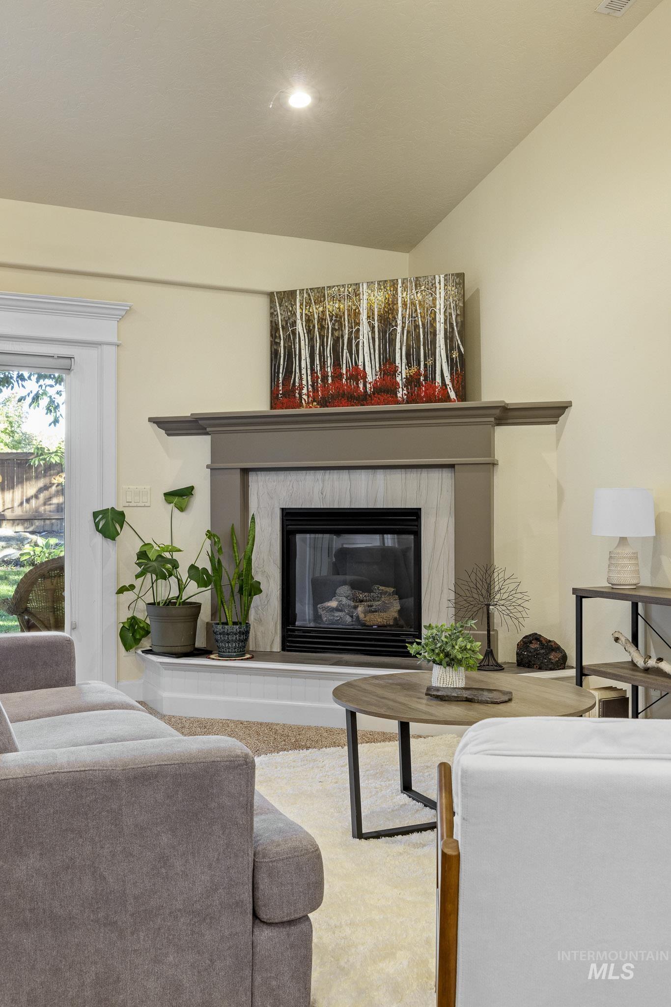 Living area featuring a high end fireplace, vaulted ceiling, and recessed lighting