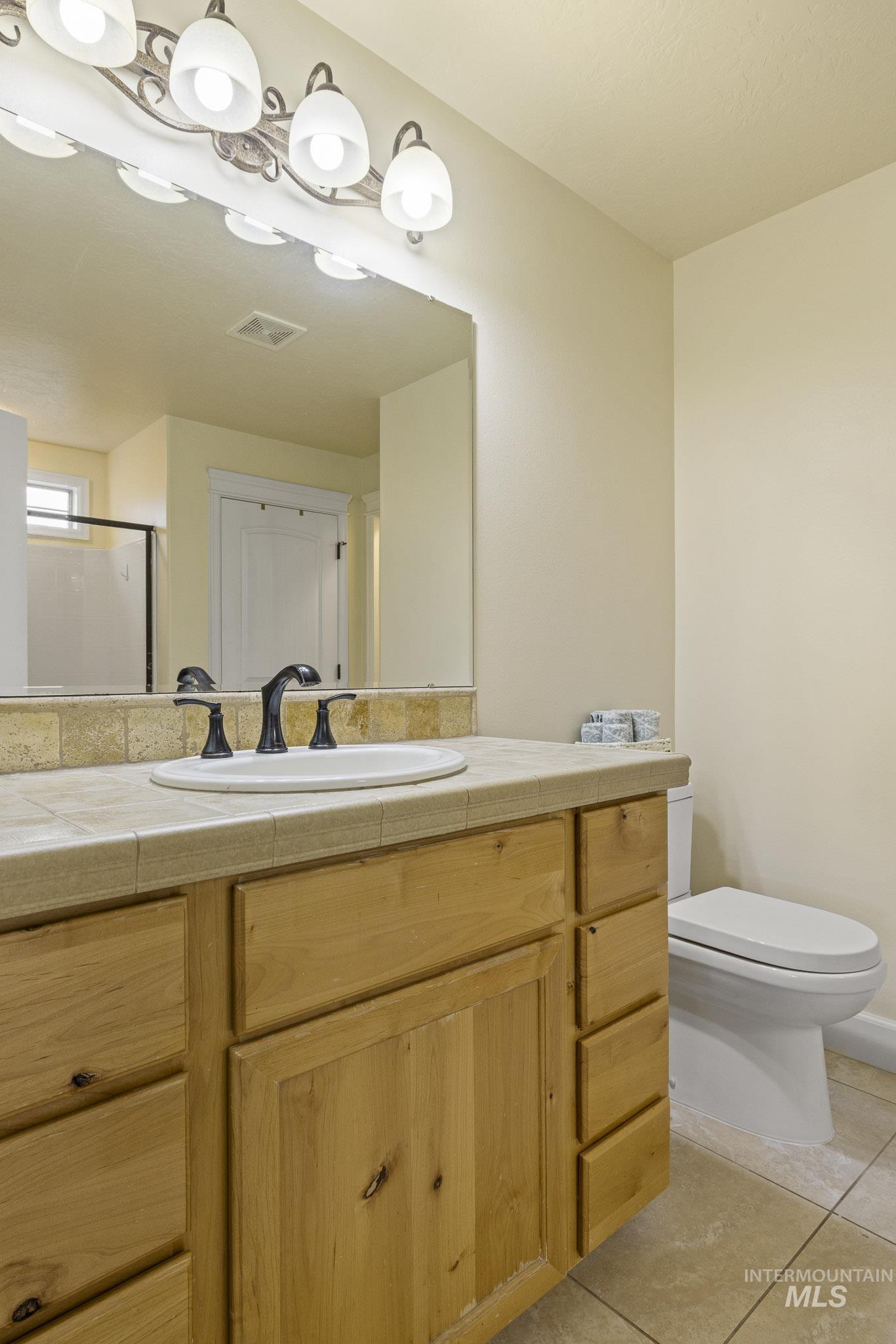 Full bathroom with vanity, light tile patterned floors, and a shower stall