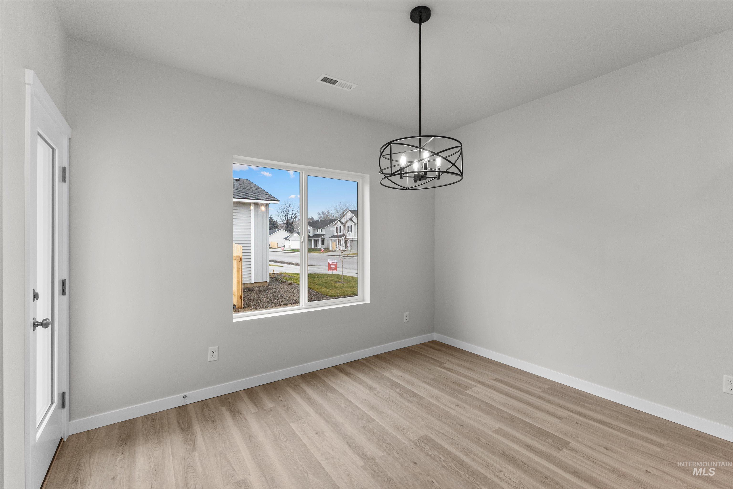 Unfurnished dining area with a chandelier and light wood-style flooring