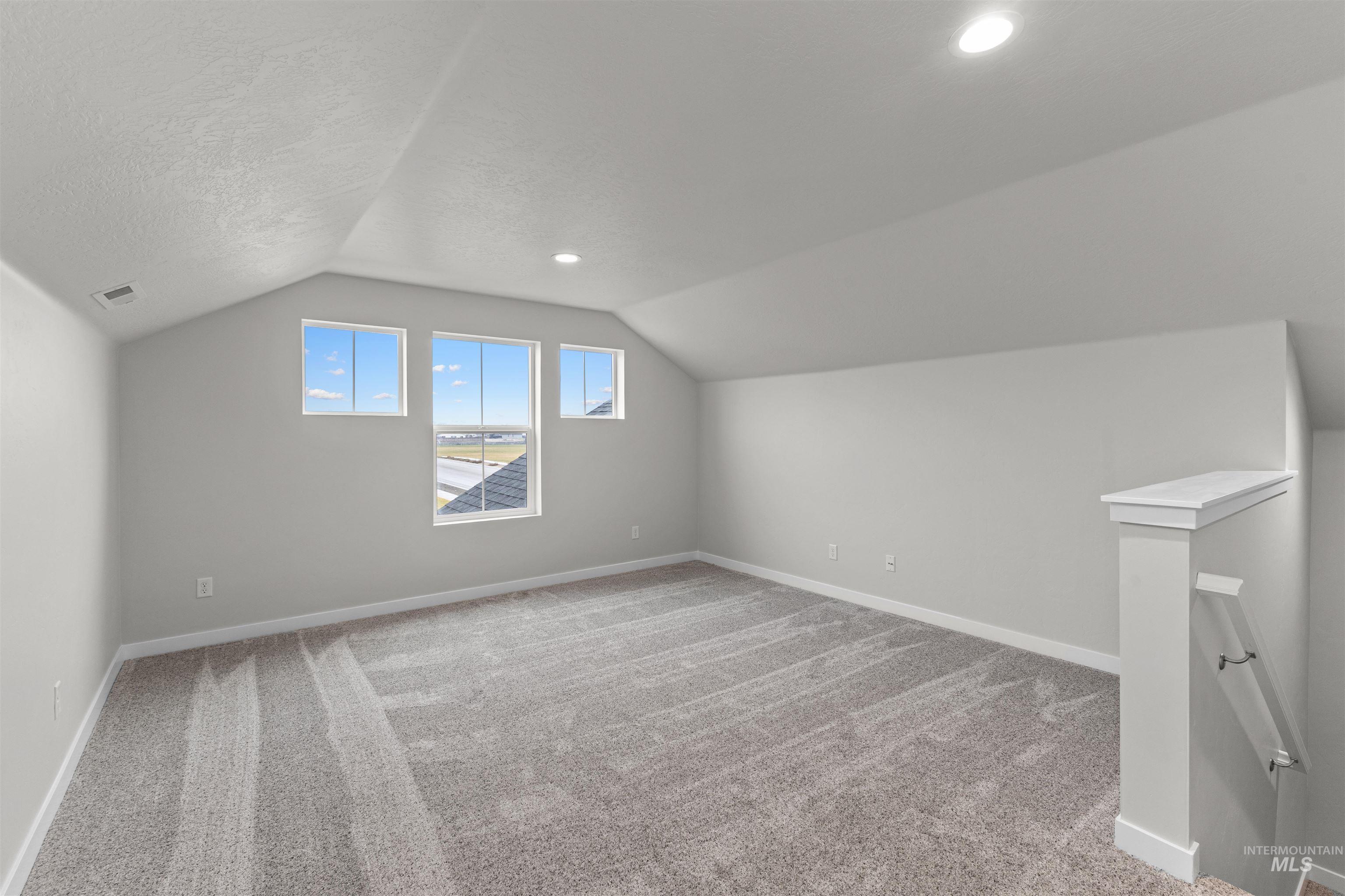 Additional living space with lofted ceiling, light carpet, recessed lighting, and a textured ceiling