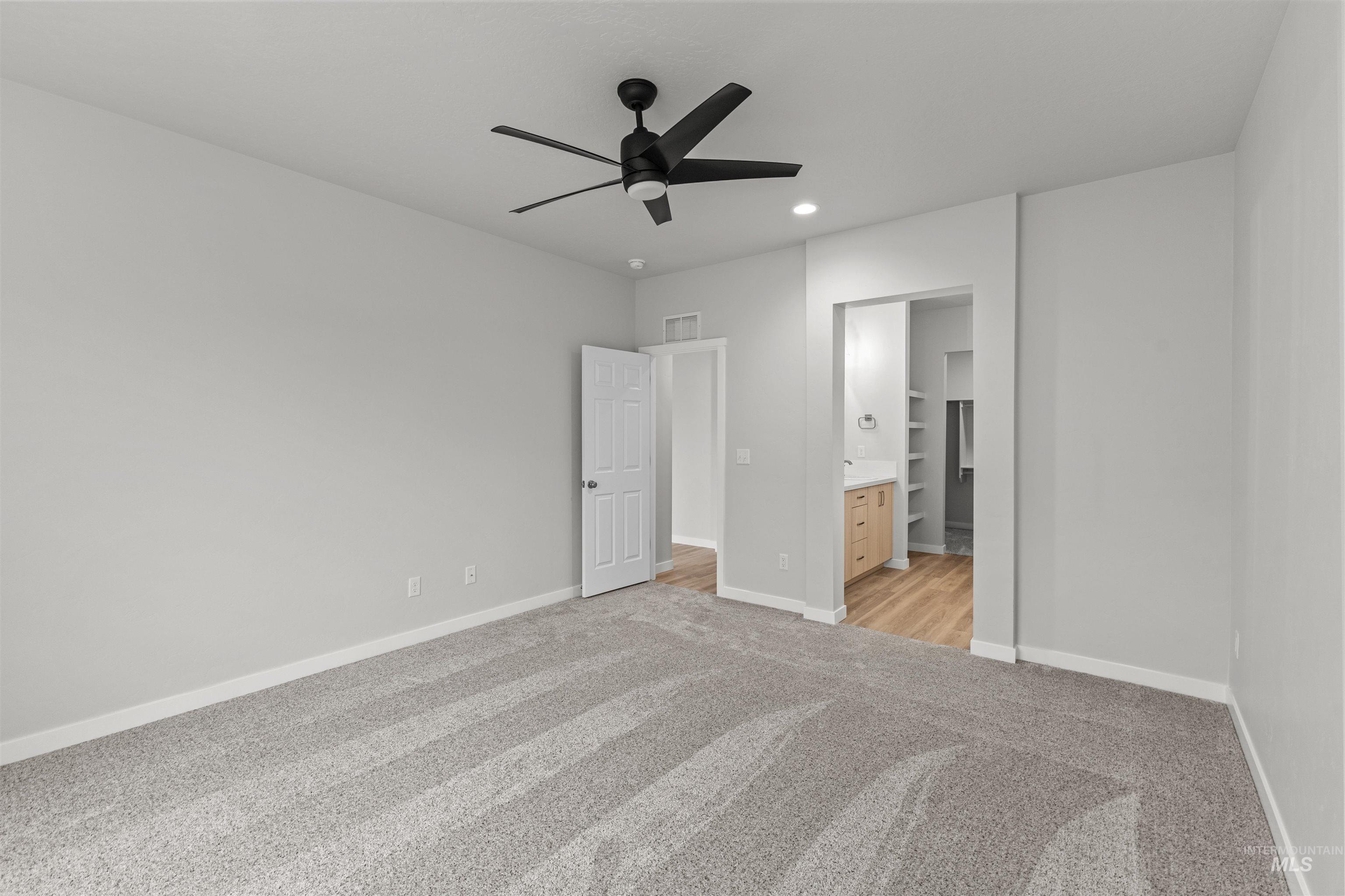 Unfurnished bedroom featuring a ceiling fan, light colored carpet, ensuite bath, and recessed lighting