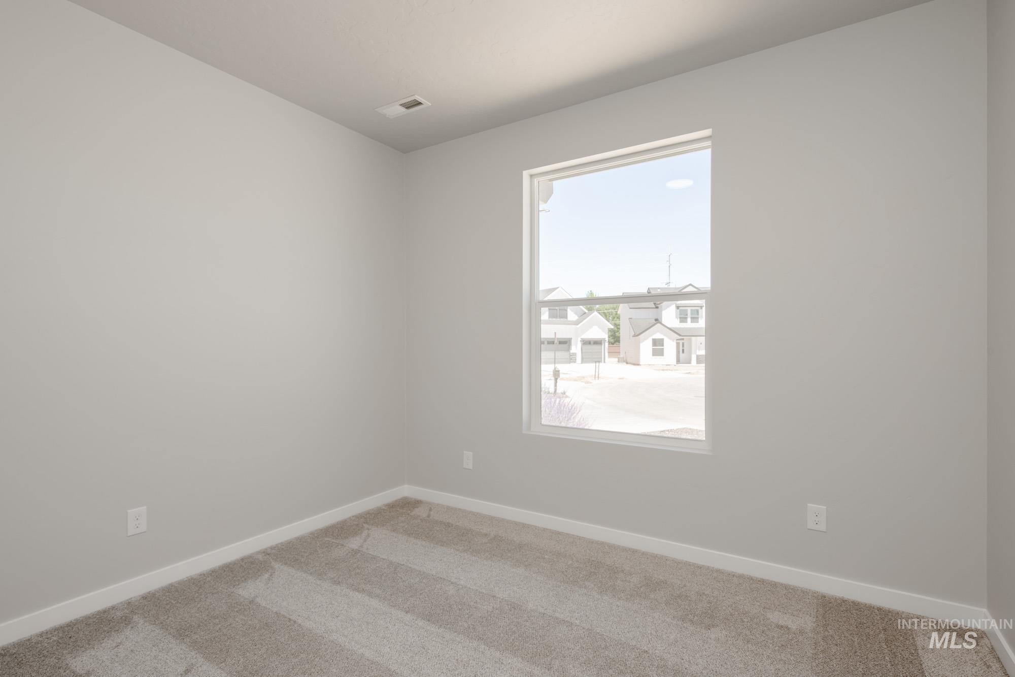 Empty room featuring light colored carpet and baseboards