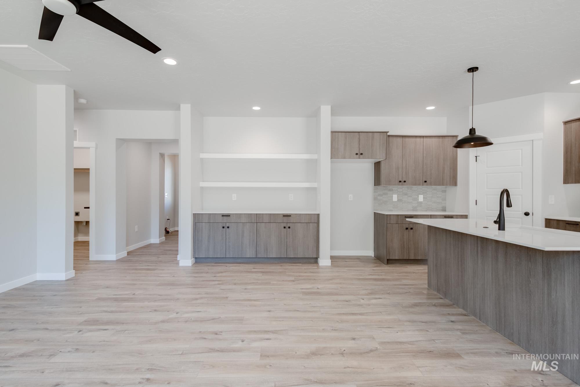 Kitchen with light countertops, a ceiling fan, light wood-type flooring, decorative backsplash, and recessed lighting
