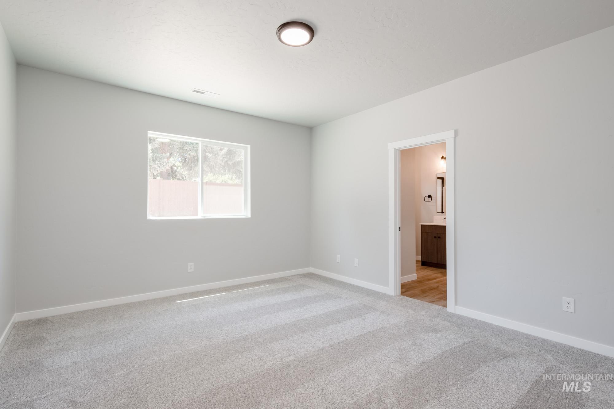 Spare room featuring light colored carpet and baseboards