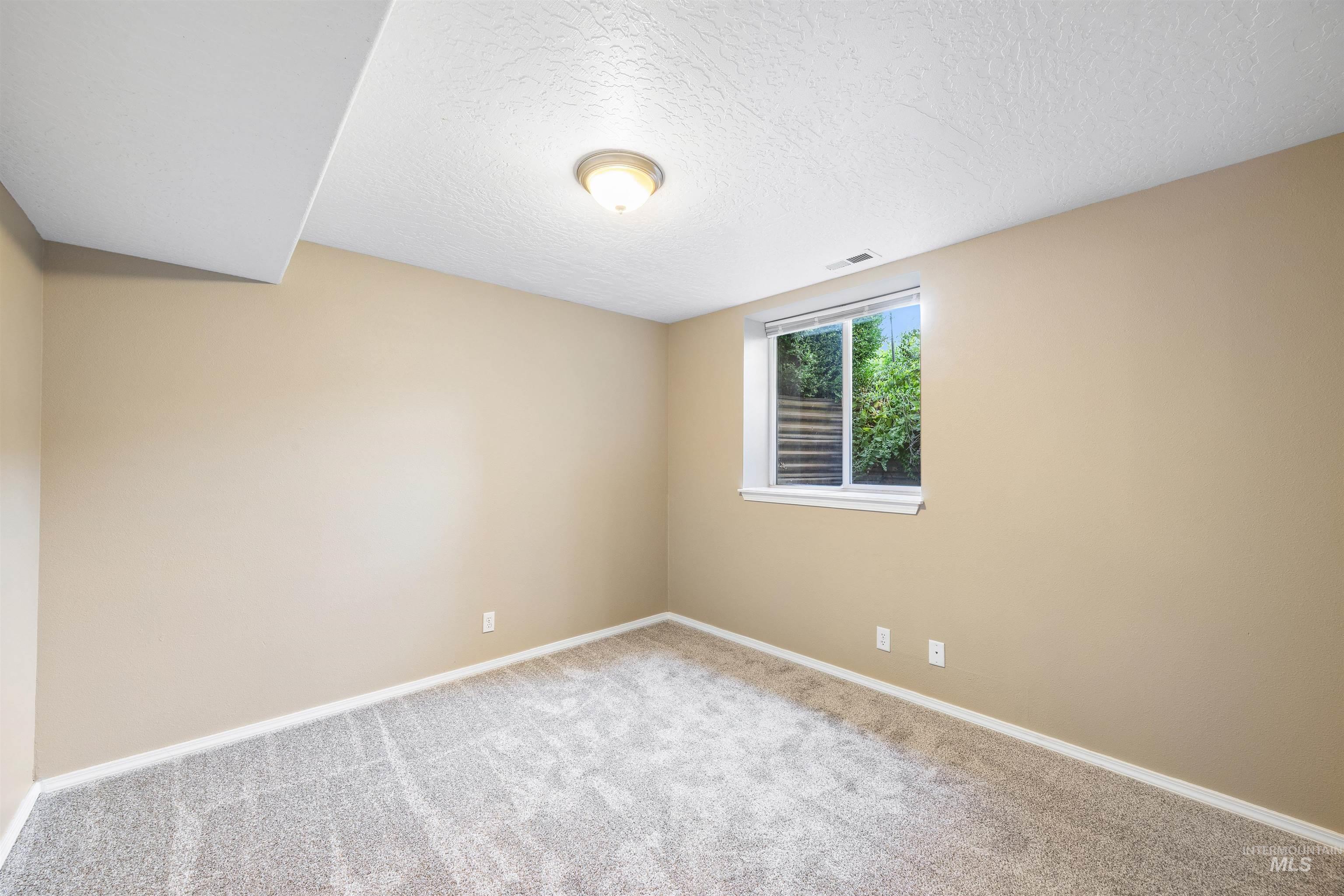 Unfurnished room featuring a textured ceiling and carpet flooring