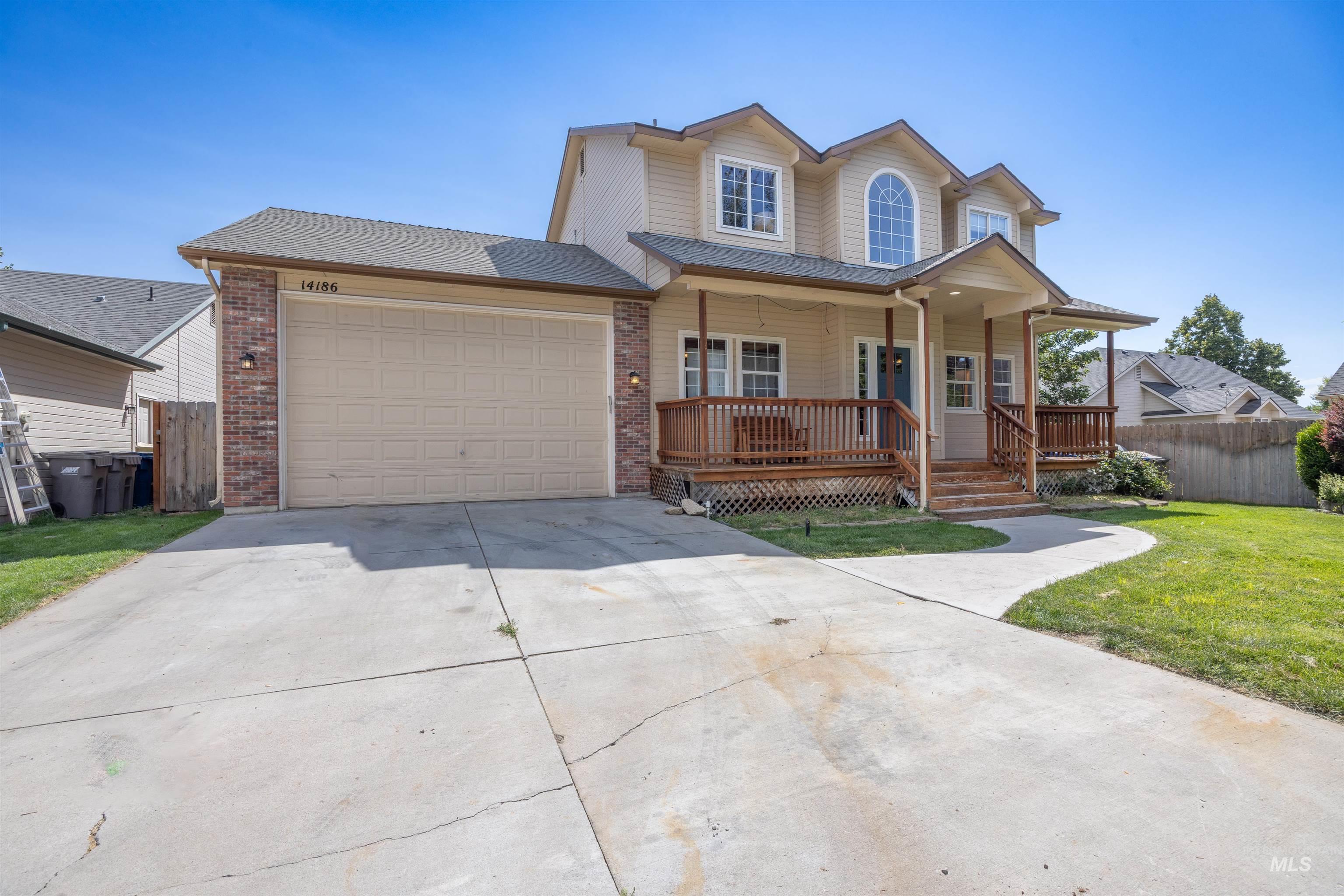 Traditional home featuring a porch, an attached garage, driveway, brick siding, and roof with shingles