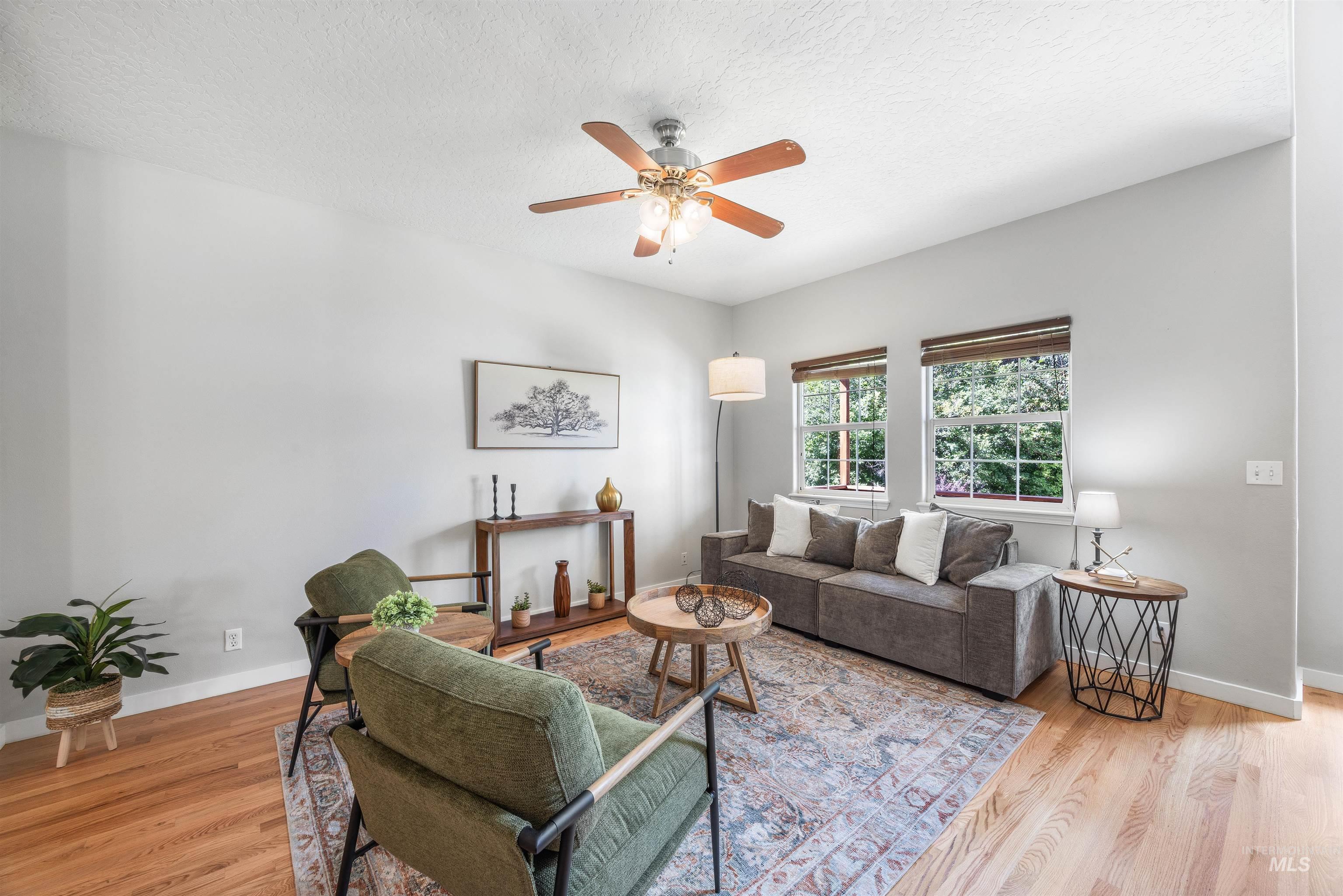Living room with light wood-style flooring, a textured ceiling, and a ceiling fan