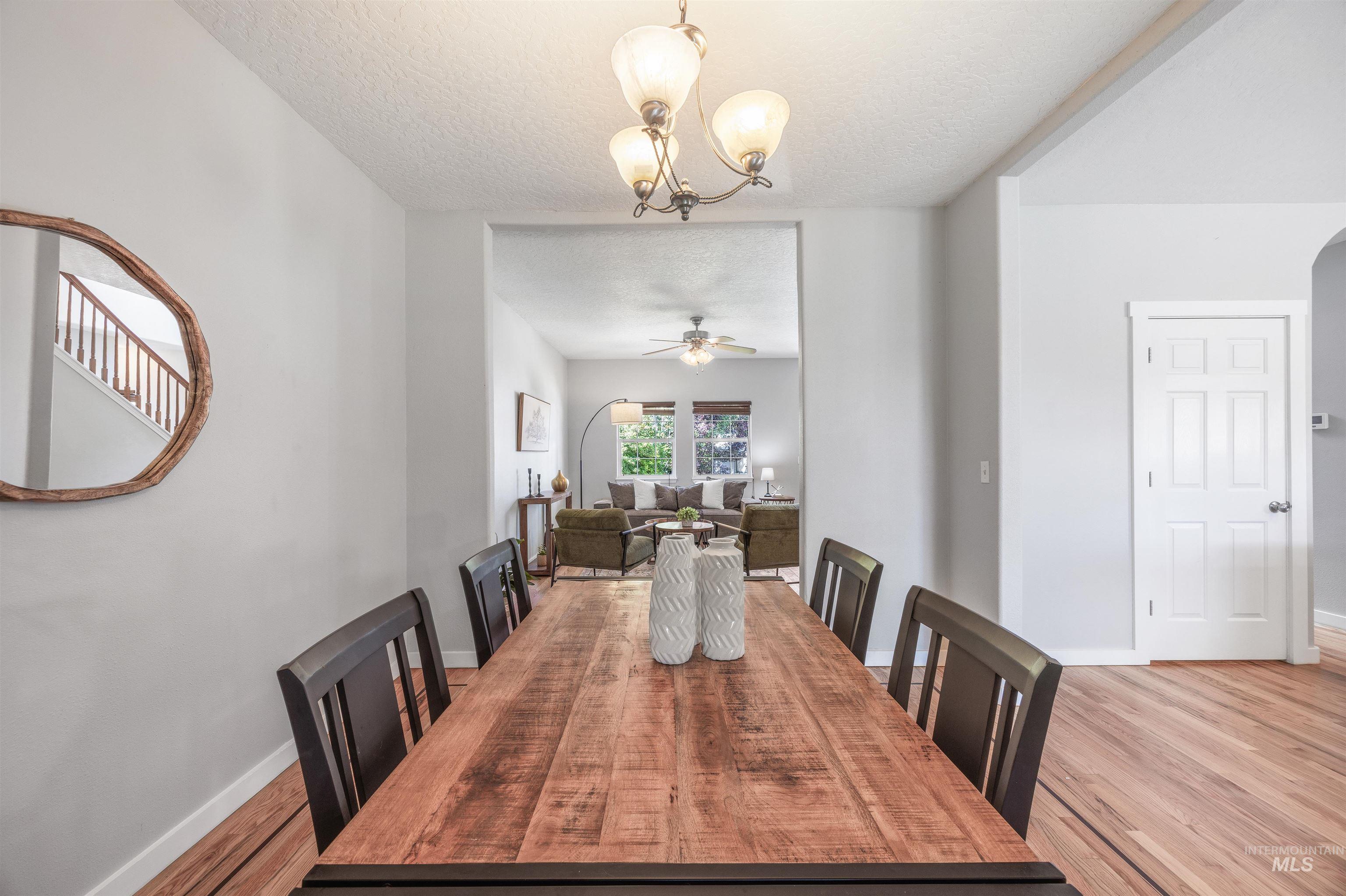 Dining space with a textured ceiling, light wood-style flooring, ceiling fan, and a chandelier