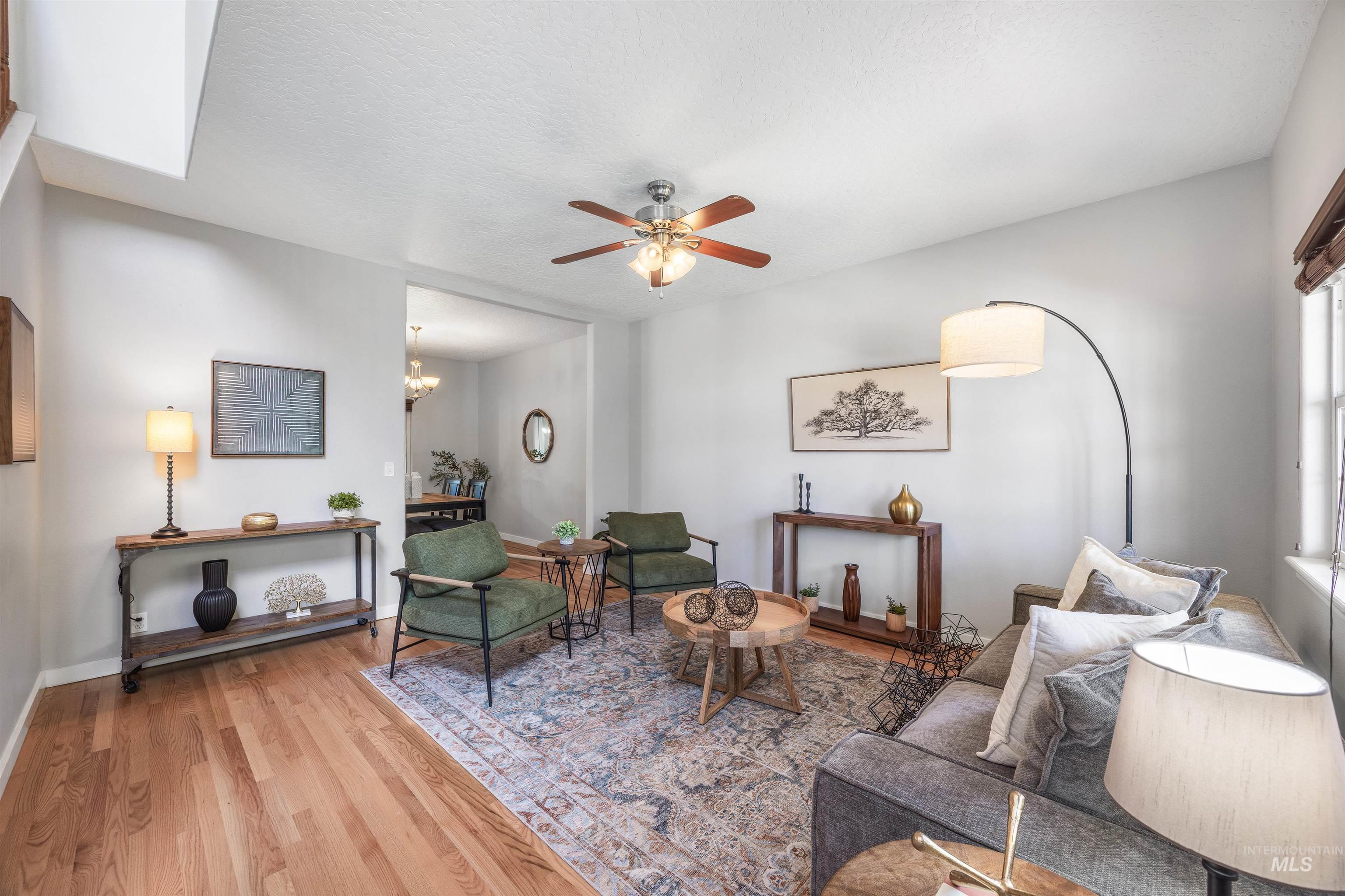 Living area with wood finished floors, a ceiling fan, a textured ceiling, and a chandelier