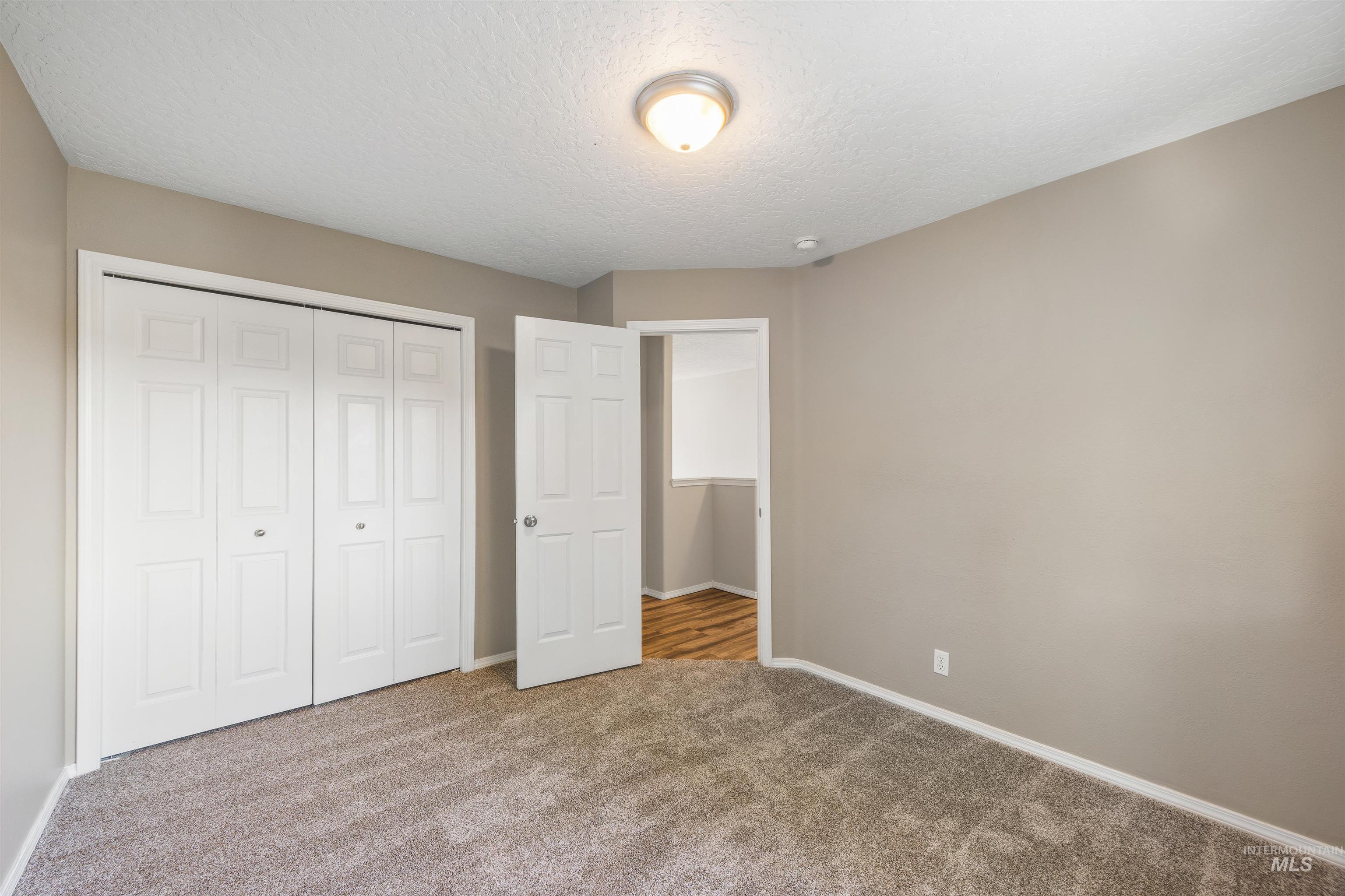 Unfurnished bedroom with a textured ceiling, carpet floors, and a closet
