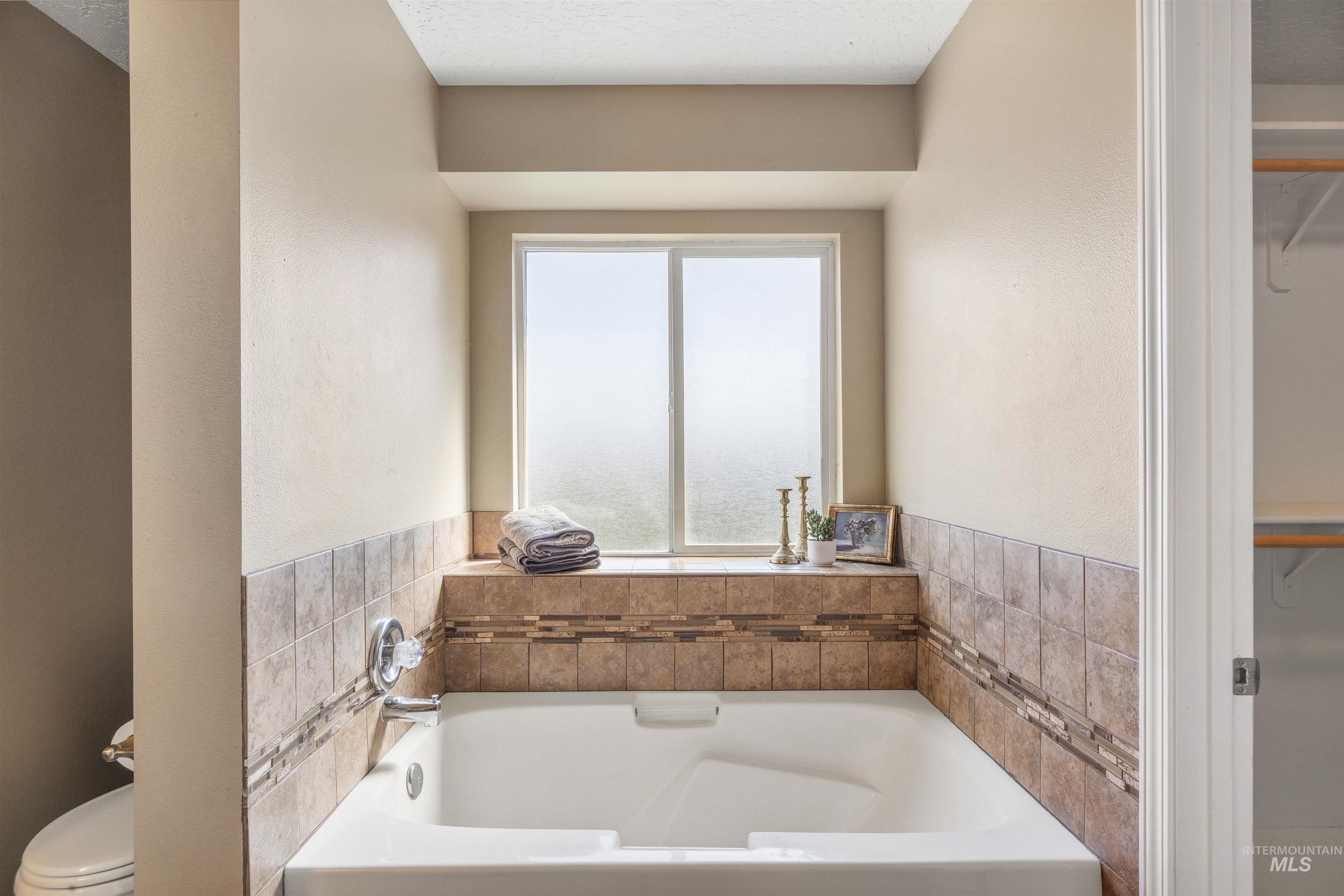 Bathroom featuring a bath, a walk in closet, and a textured wall
