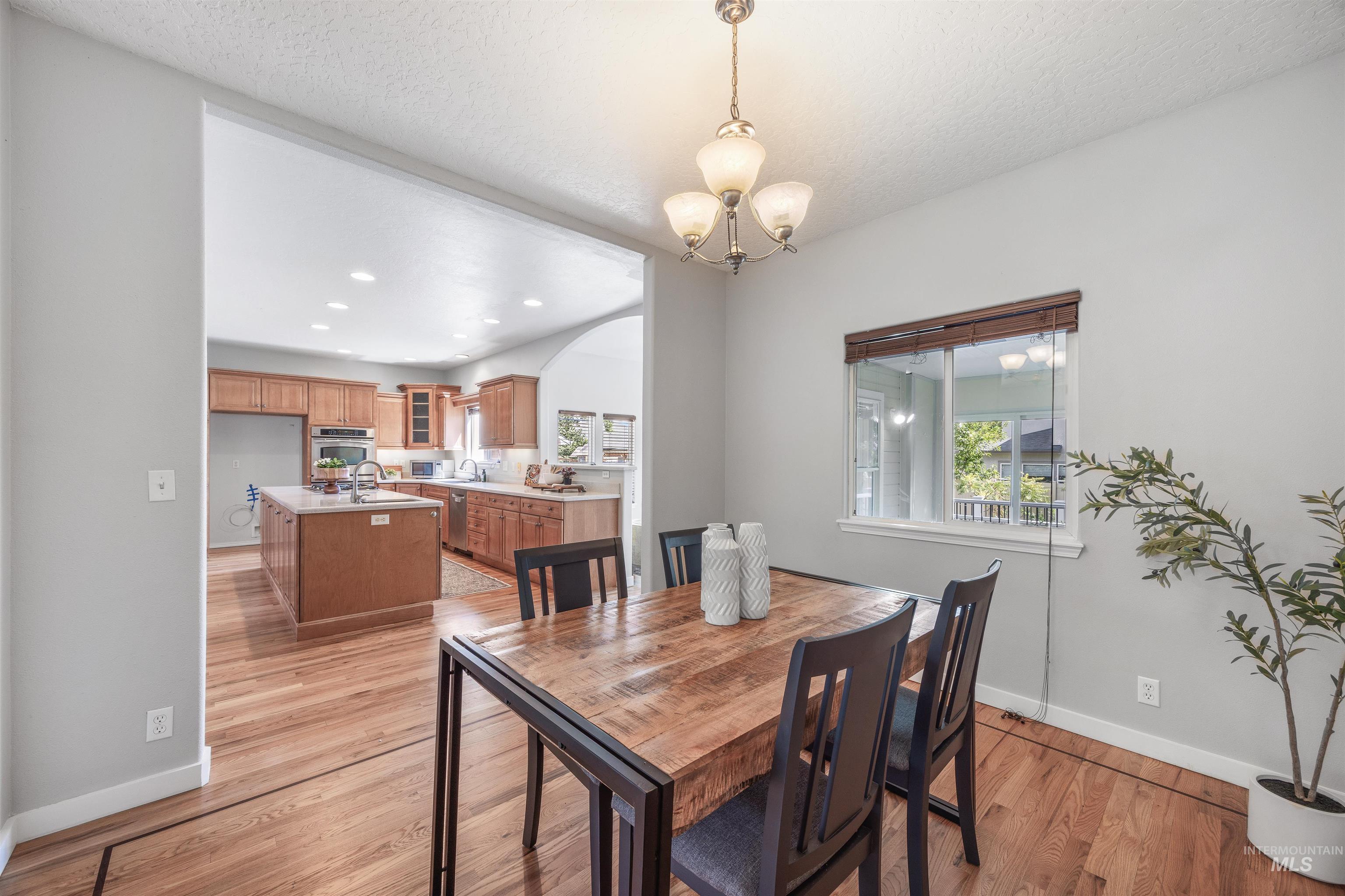 Dining space with light wood-type flooring, recessed lighting, a textured ceiling, and a chandelier