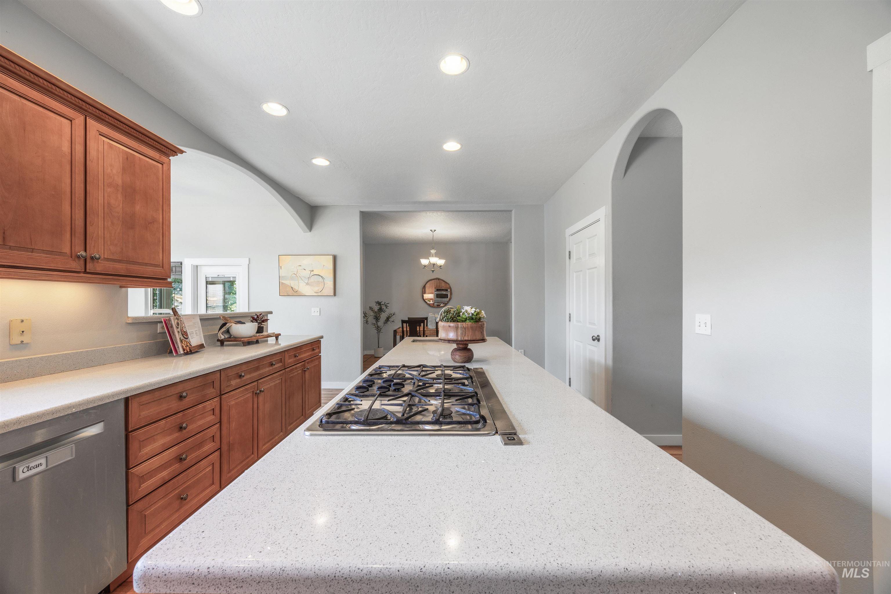 Kitchen featuring appliances with stainless steel finishes, recessed lighting, a chandelier, a kitchen island, and arched walkways
