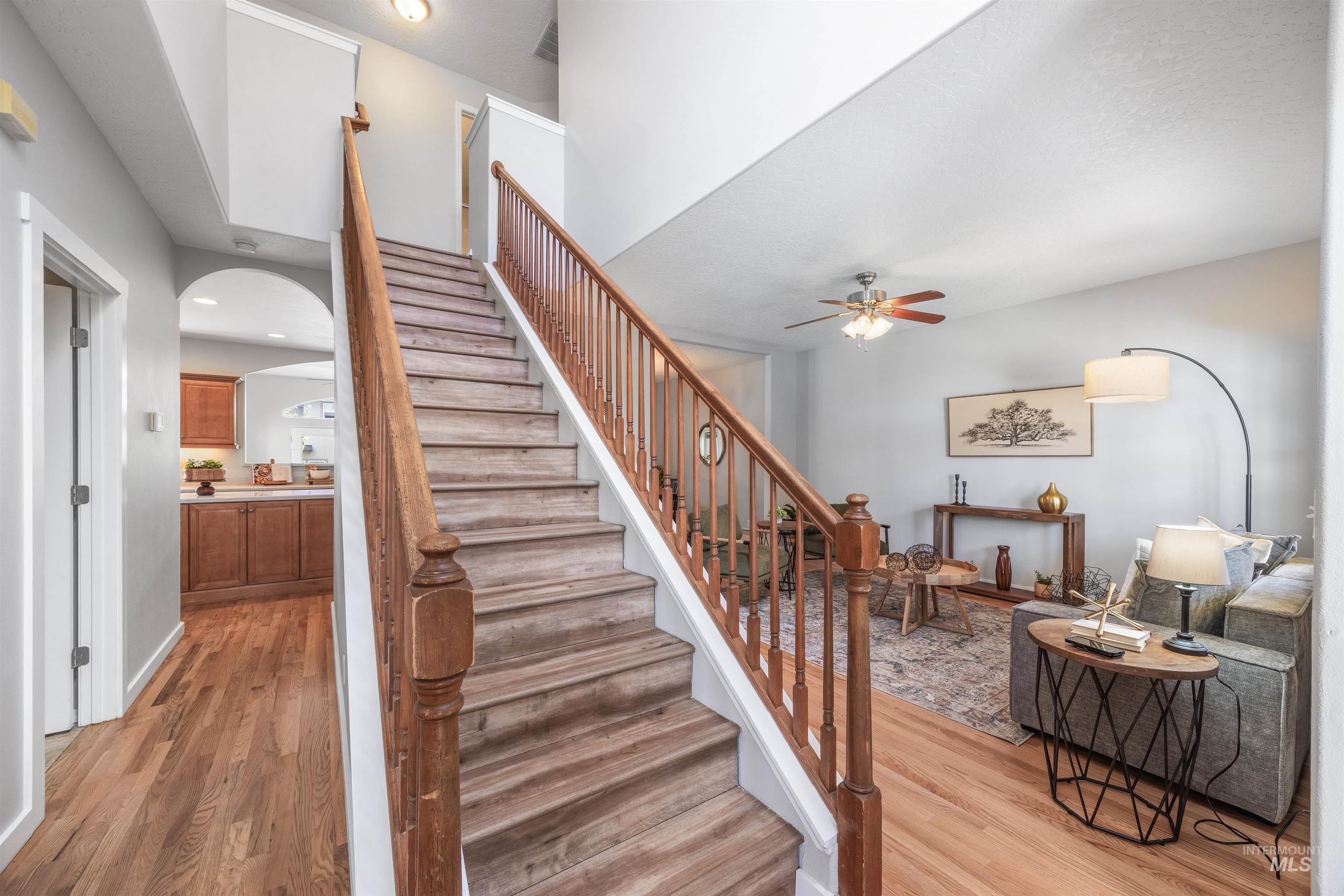 Staircase with wood finished floors, arched walkways, and a ceiling fan