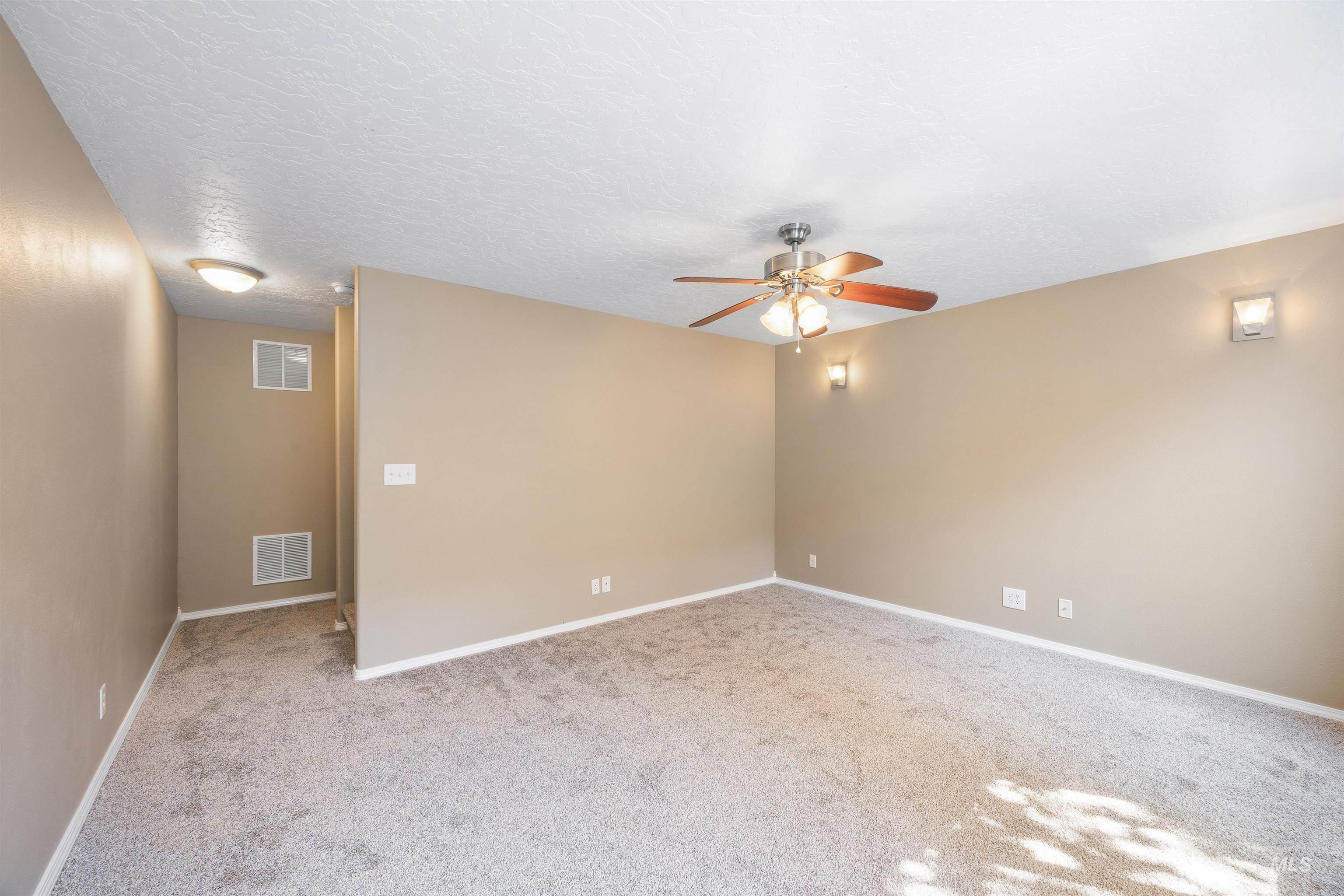 Unfurnished room featuring light carpet, a textured ceiling, and a ceiling fan