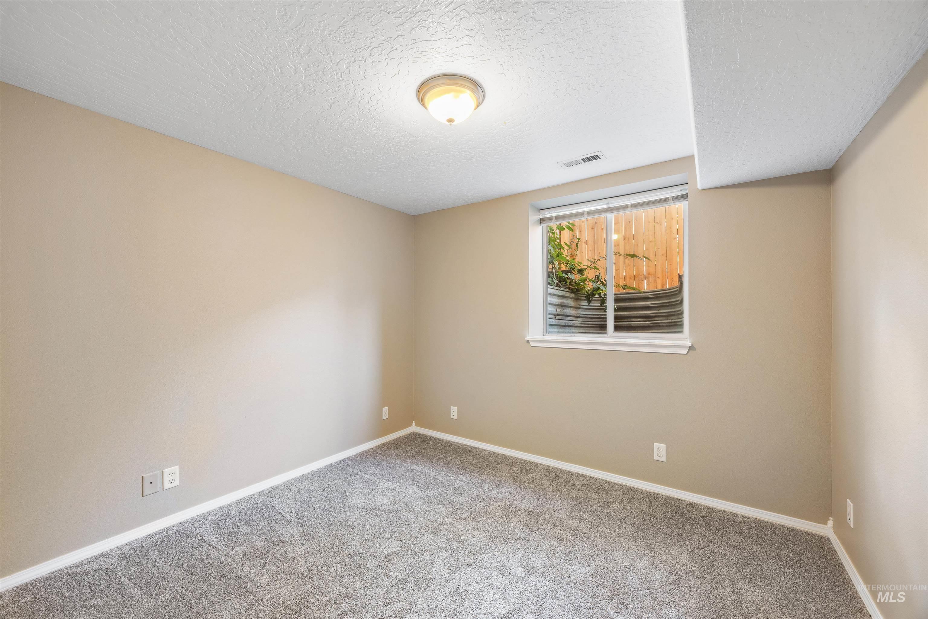 Carpeted empty room featuring a textured ceiling and baseboards