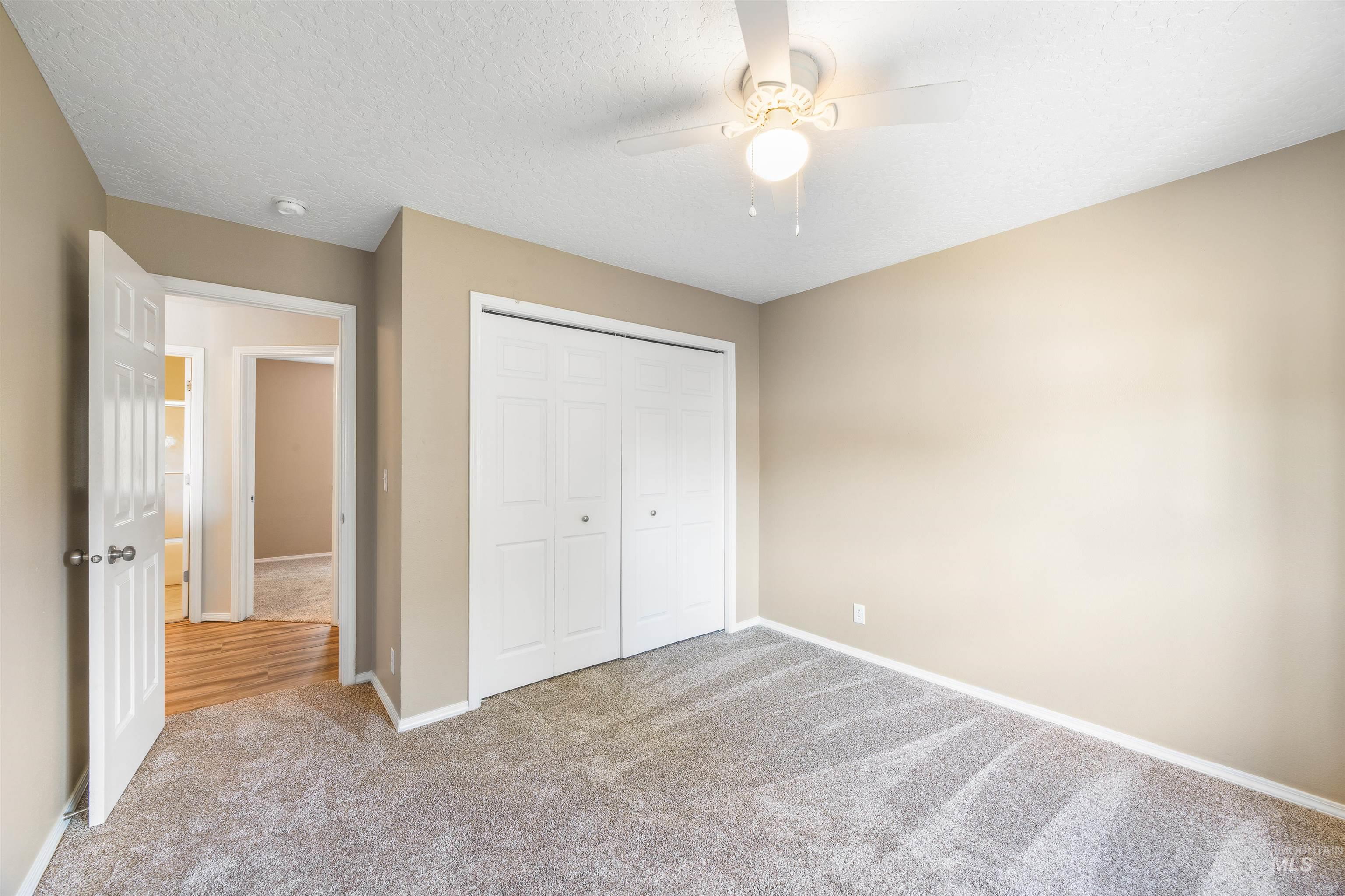 Unfurnished bedroom featuring carpet, a closet, a textured ceiling, and a ceiling fan