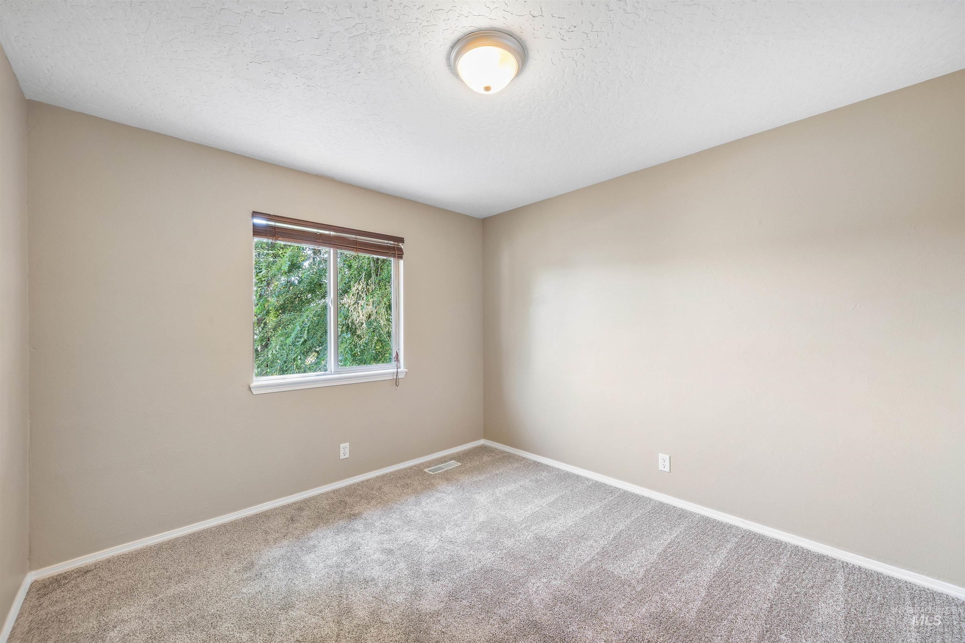 Carpeted spare room with baseboards and a textured ceiling
