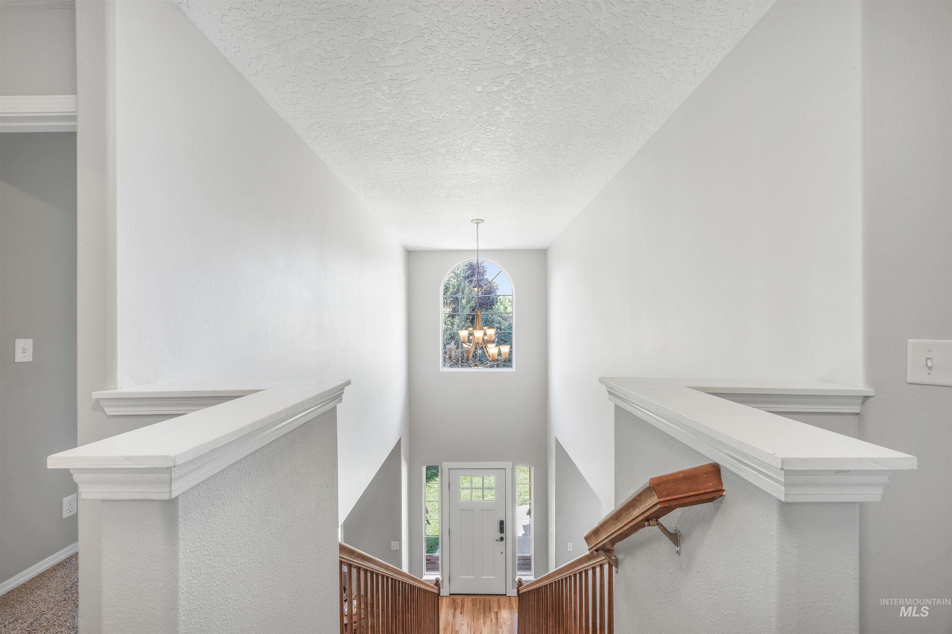 Stairway with a chandelier, healthy amount of natural light, a high ceiling, and a textured ceiling