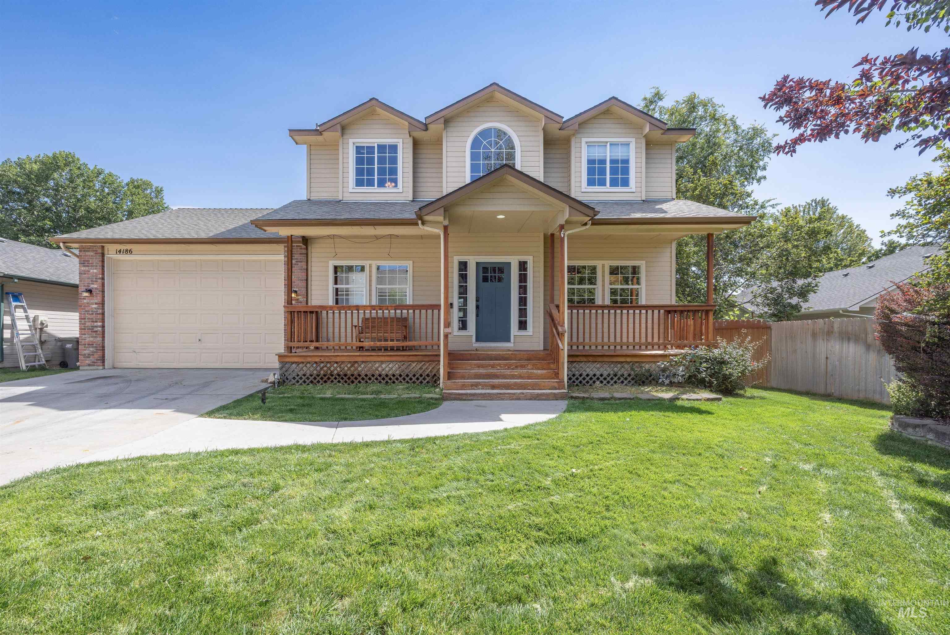 View of front of home with covered porch, an attached garage, driveway, and a front yard
