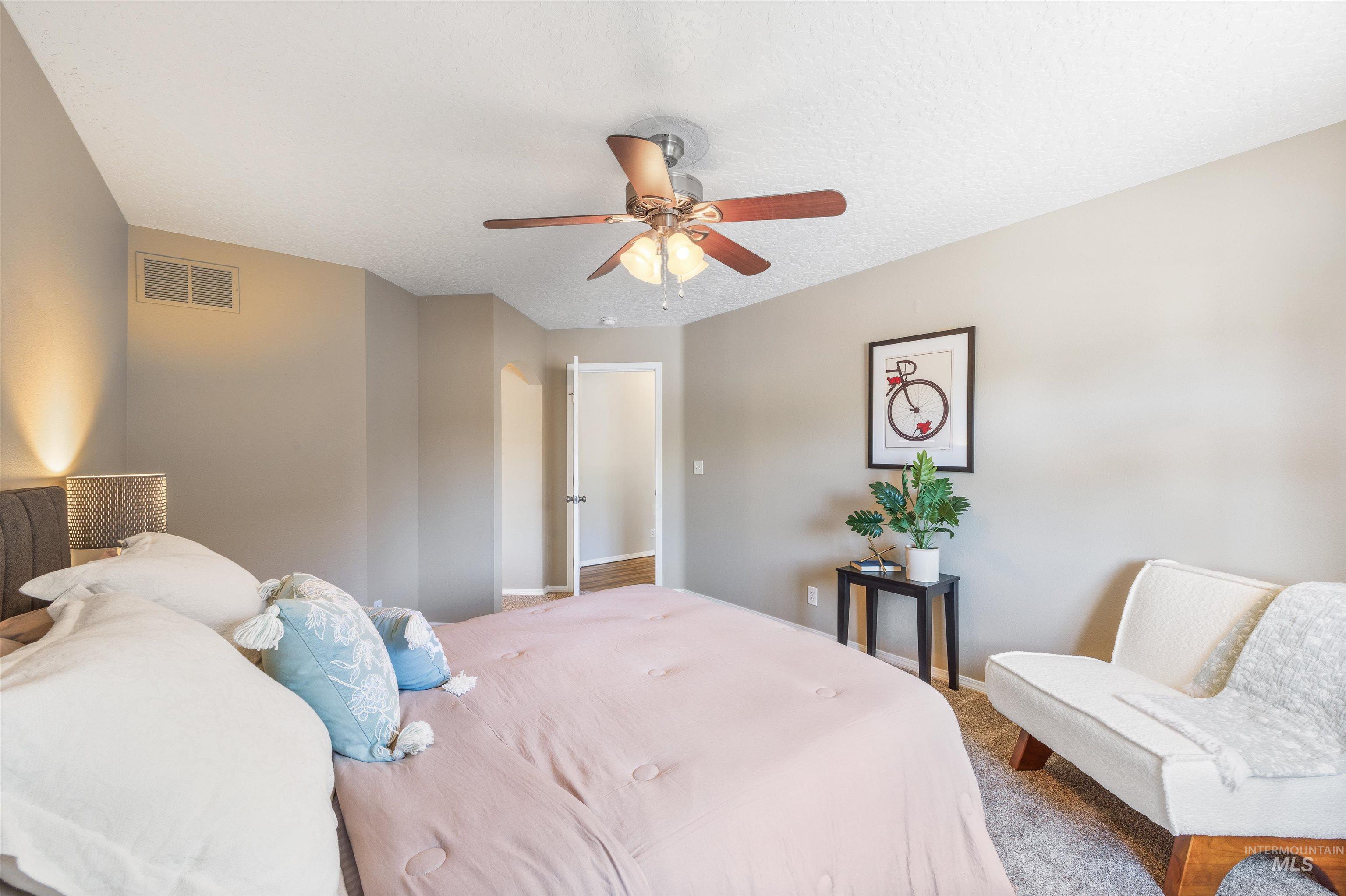 Carpeted bedroom featuring ceiling fan and a textured ceiling