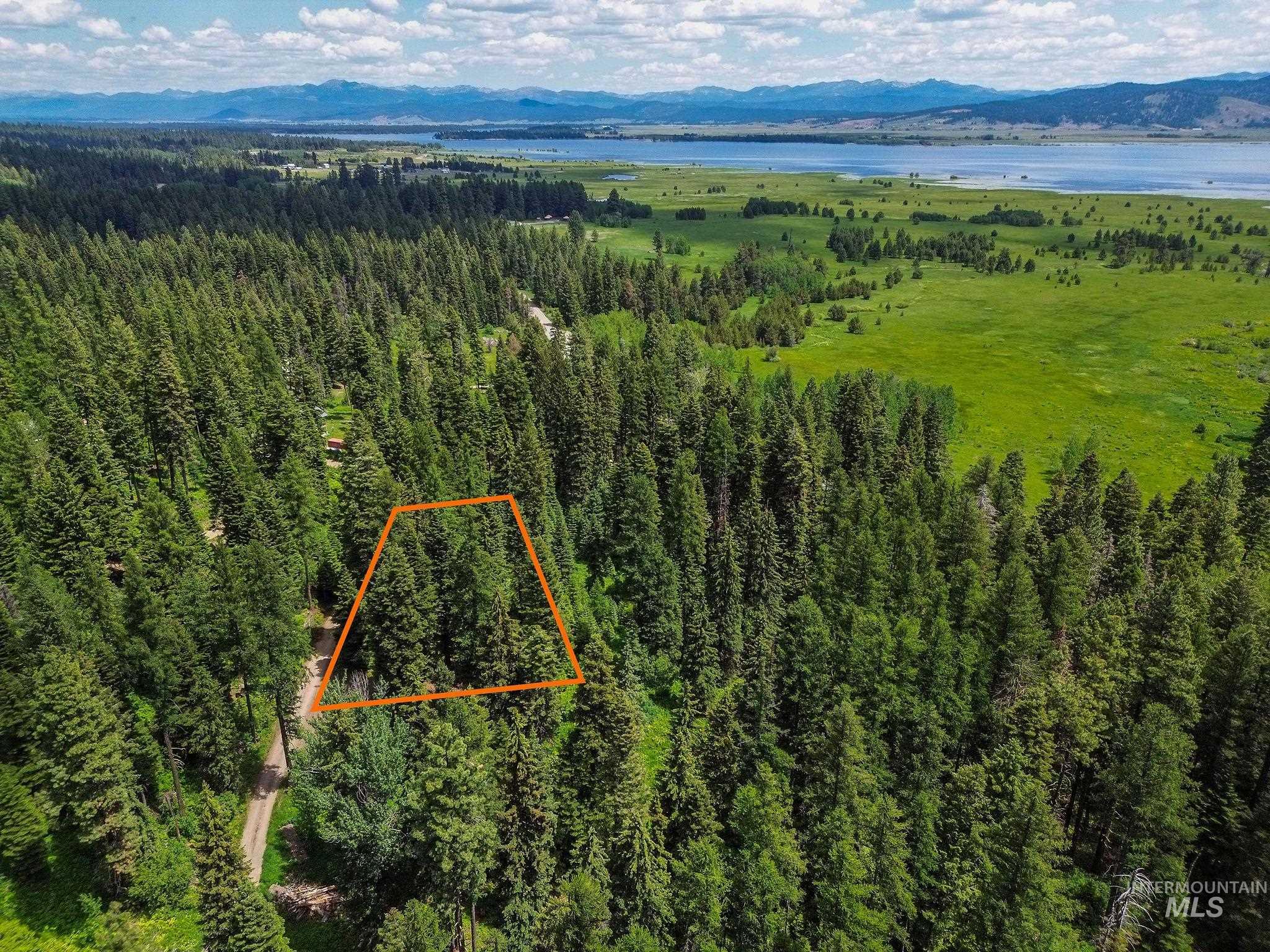 Aerial view of property and surrounding area with a water and mountain view and property parcel outlined