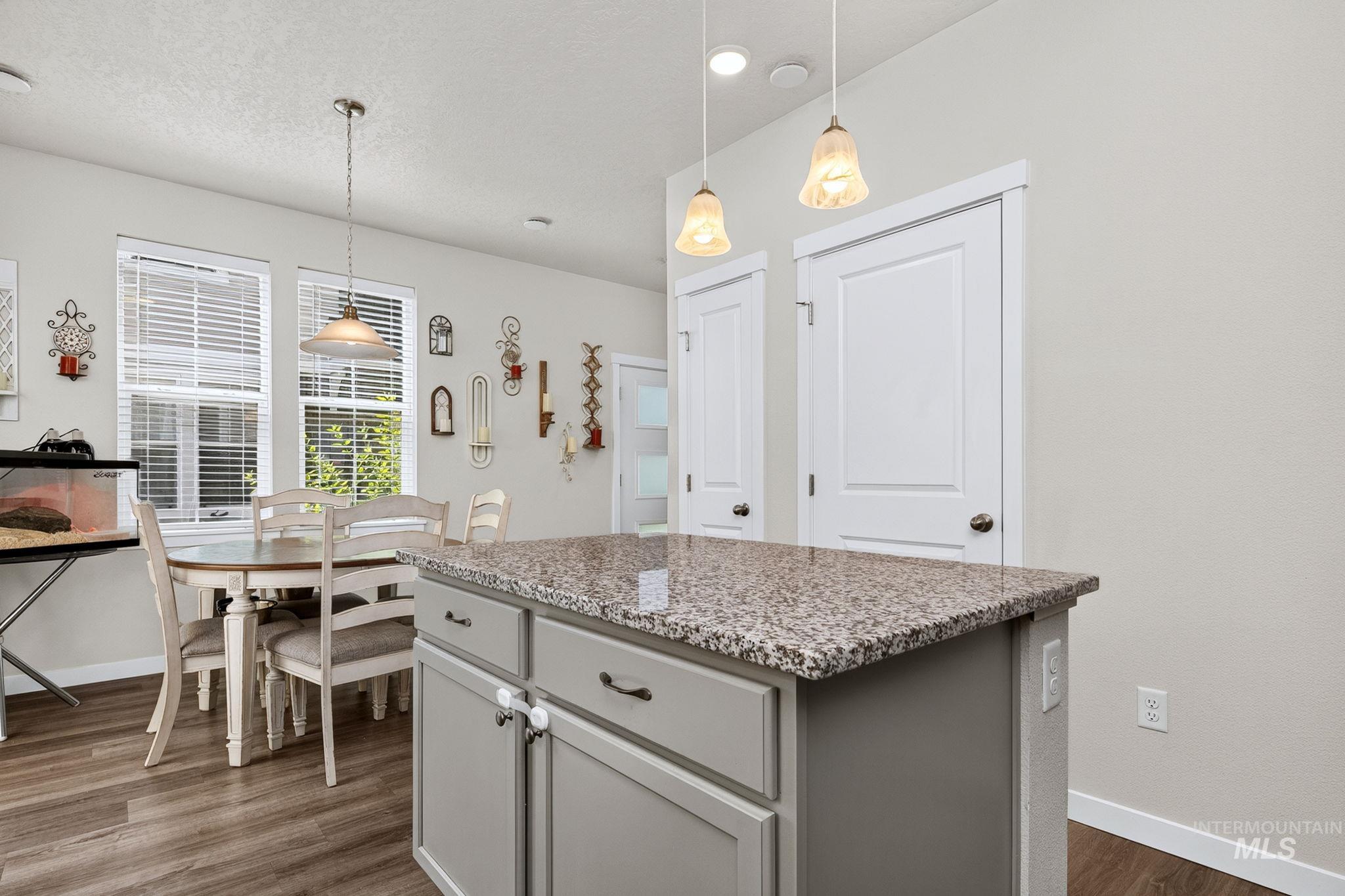 Kitchen island featuring a speckled countertop, pendant lighting, and gray cabinetry