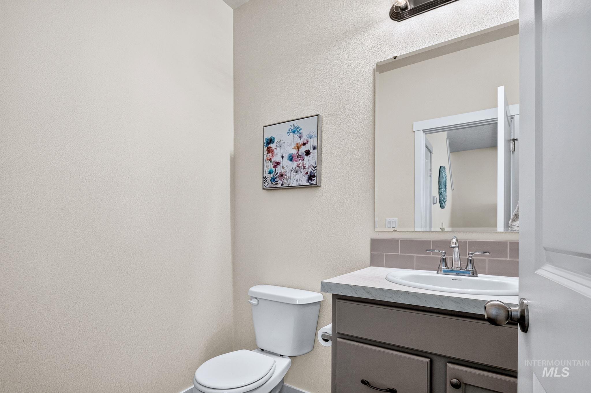 Powder room featuring a single vanity with a white countertop, inset sink, and a gray subway tile backsplash