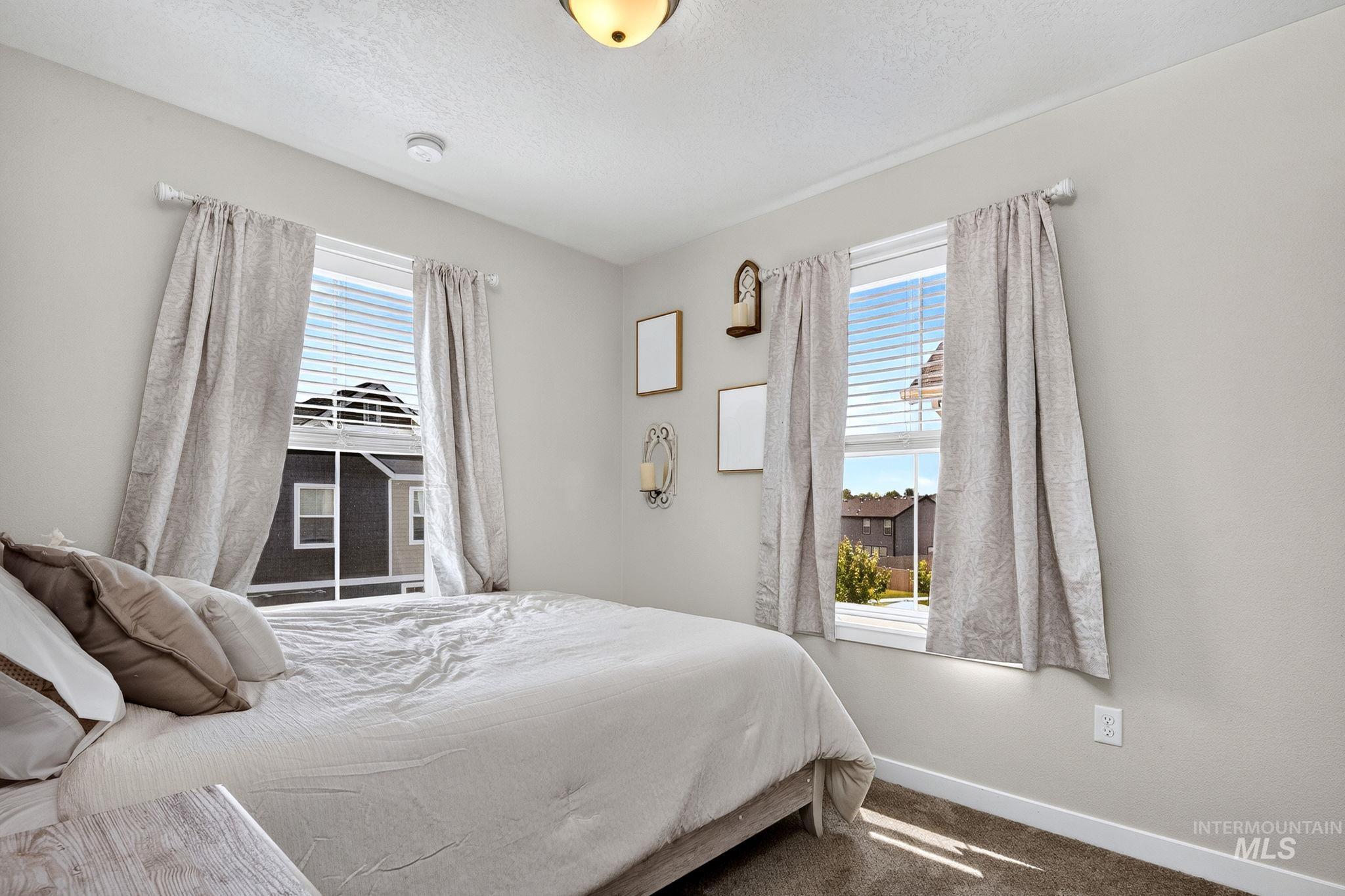 Bedroom featuring light gray walls and two windows with white blinds
