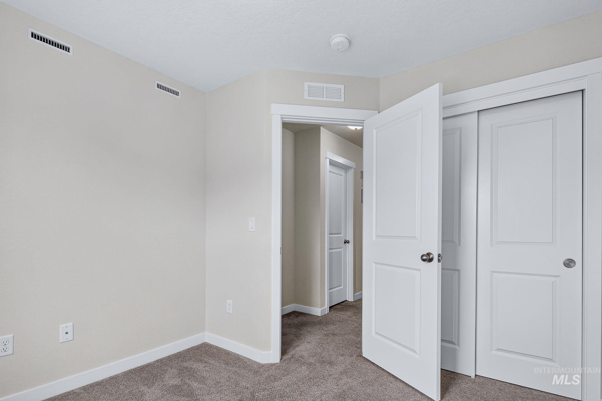 Carpeted room featuring a white paneled door, sliding closet doors, and light neutral walls