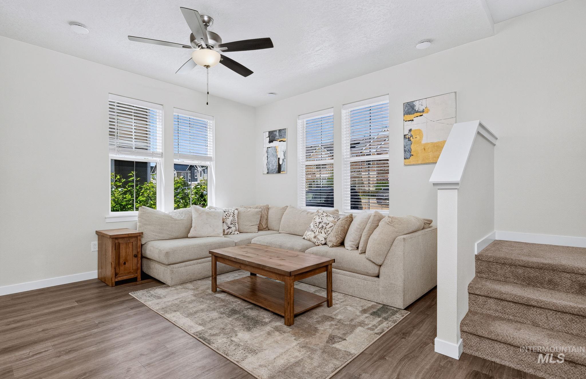 Living area featuring wood-finish flooring, recessed lighting, and a ceiling fan with integrated light