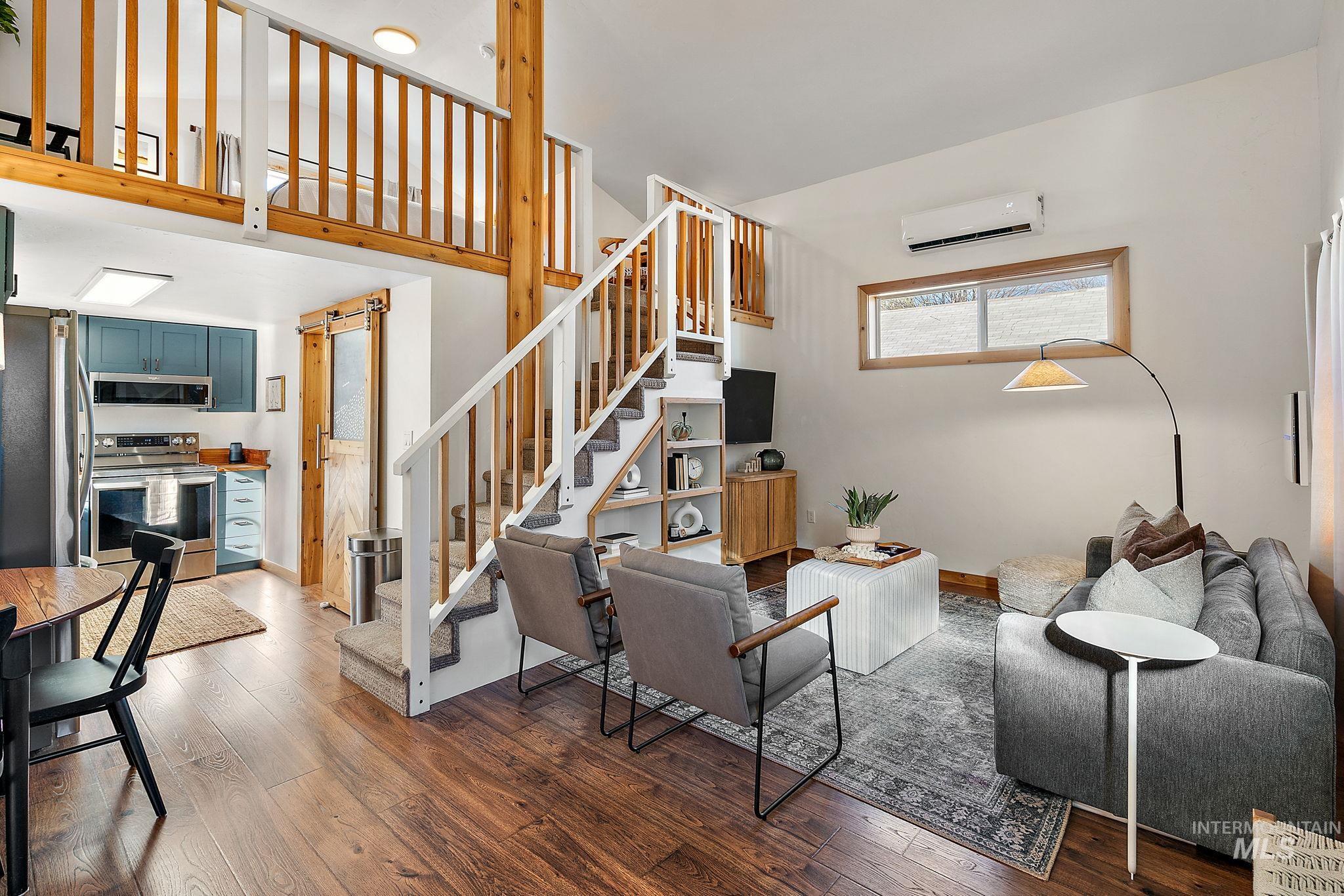 Living room with hardwood / wood-style floors, a wall mounted air conditioner, and stairway