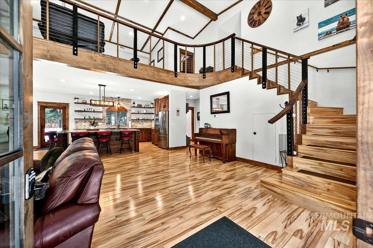 Living room featuring light wood-finish laminate flooring, recessed lighting, and a soaring ceiling