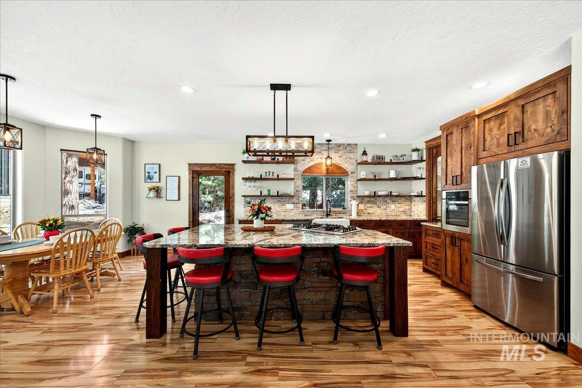 Stainless steel appliances, huge kitchen island with doubler-sided breakfast bar, open shelves with underlighting