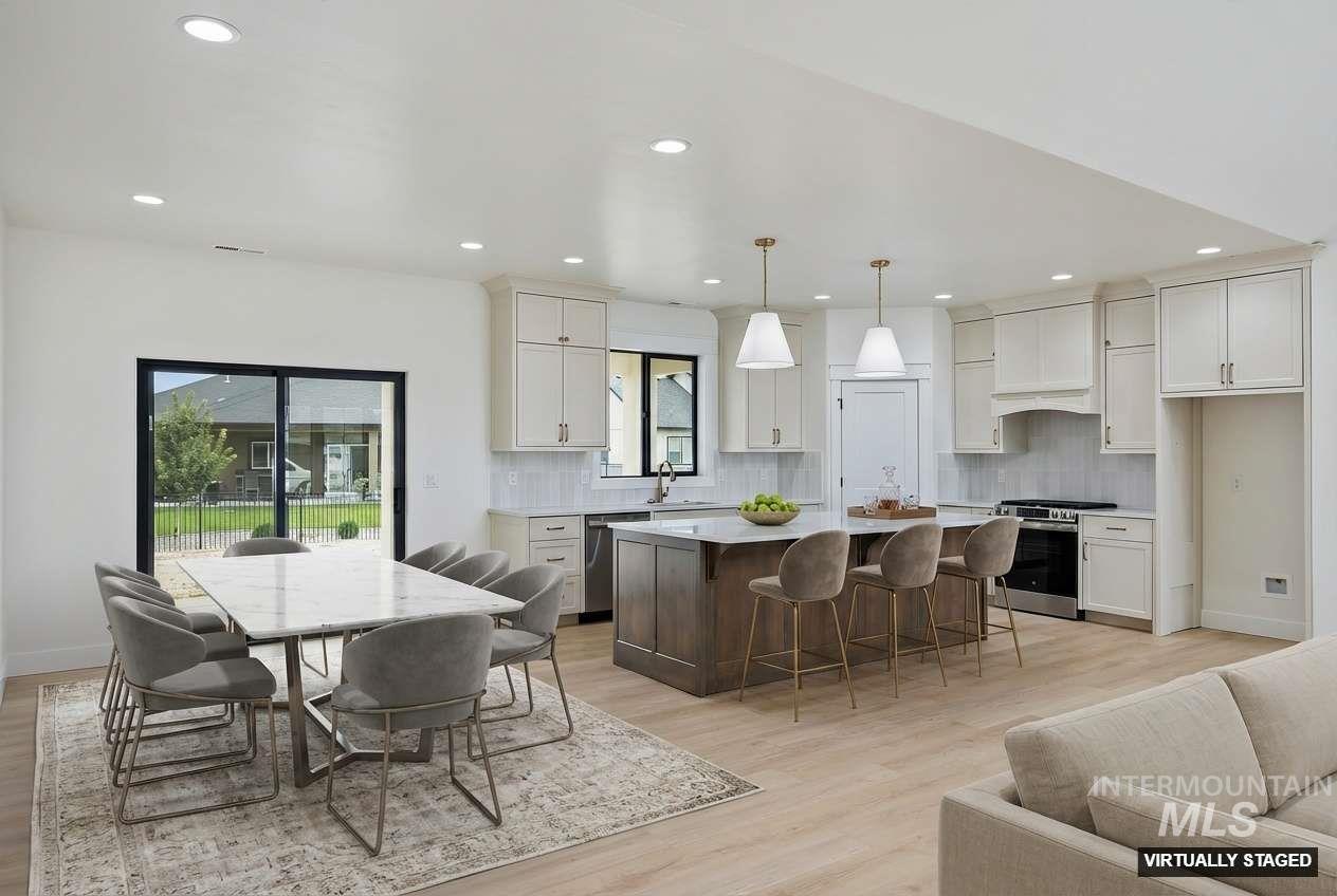 Kitchen with stainless steel appliances, a center island, a kitchen breakfast bar, backsplash, and light wood-style floors