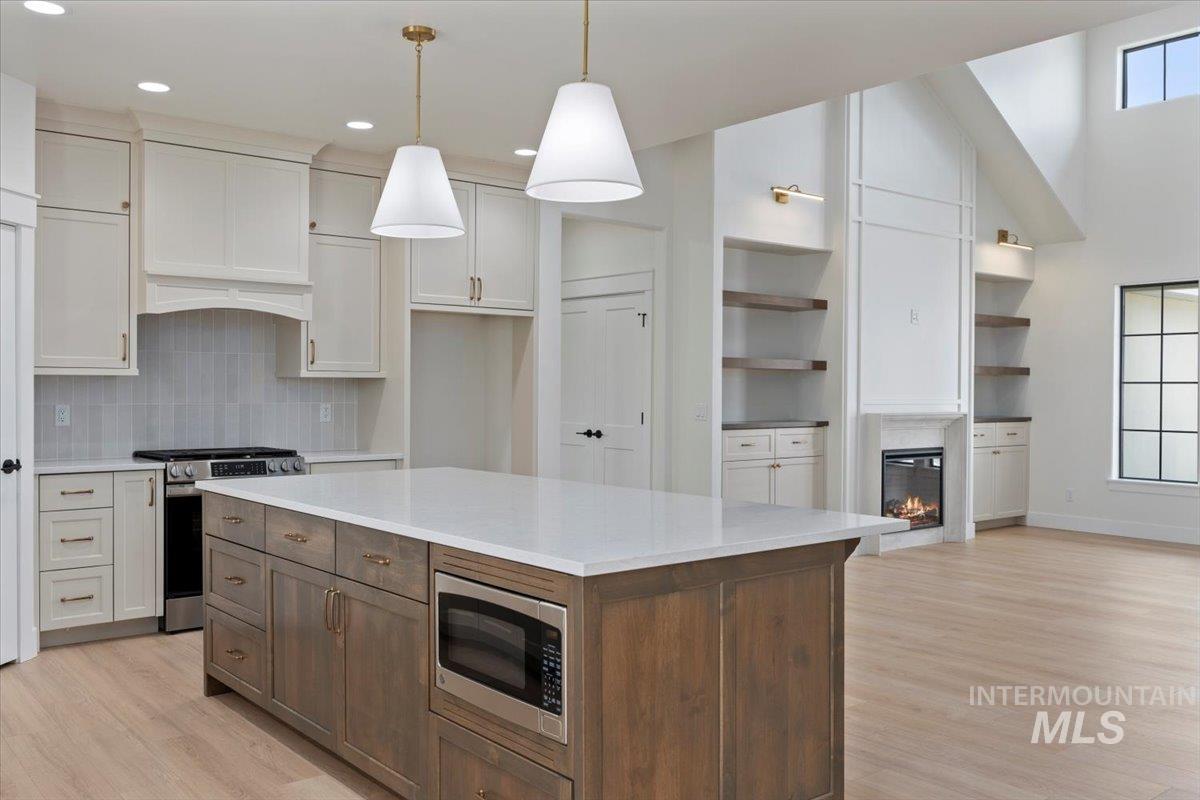 Kitchen featuring a center island, stainless steel appliances, light wood-style floors, light stone counters, and plenty of natural light