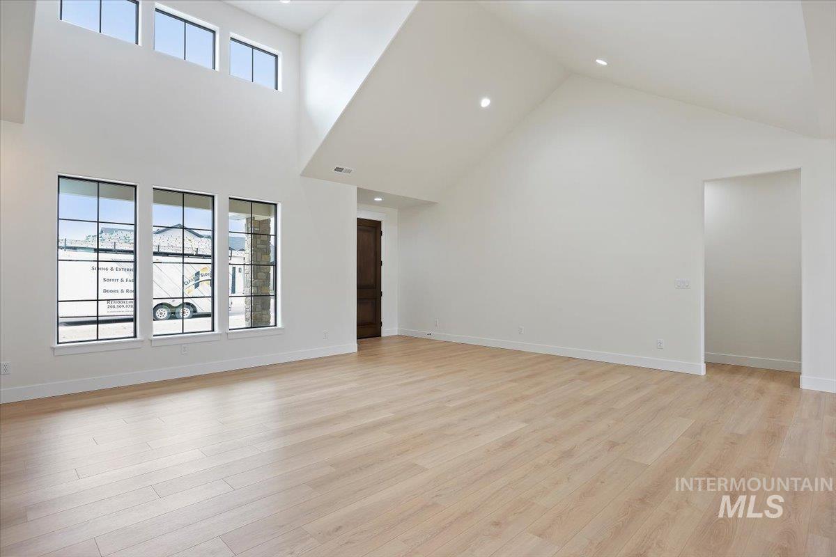 Unfurnished living room featuring high vaulted ceiling, light wood-style floors, and recessed lighting
