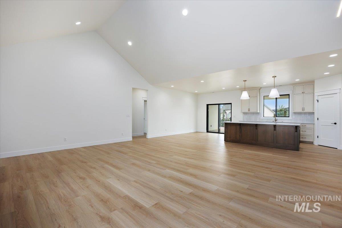 Unfurnished living room with recessed lighting, light wood-style floors, and high vaulted ceiling